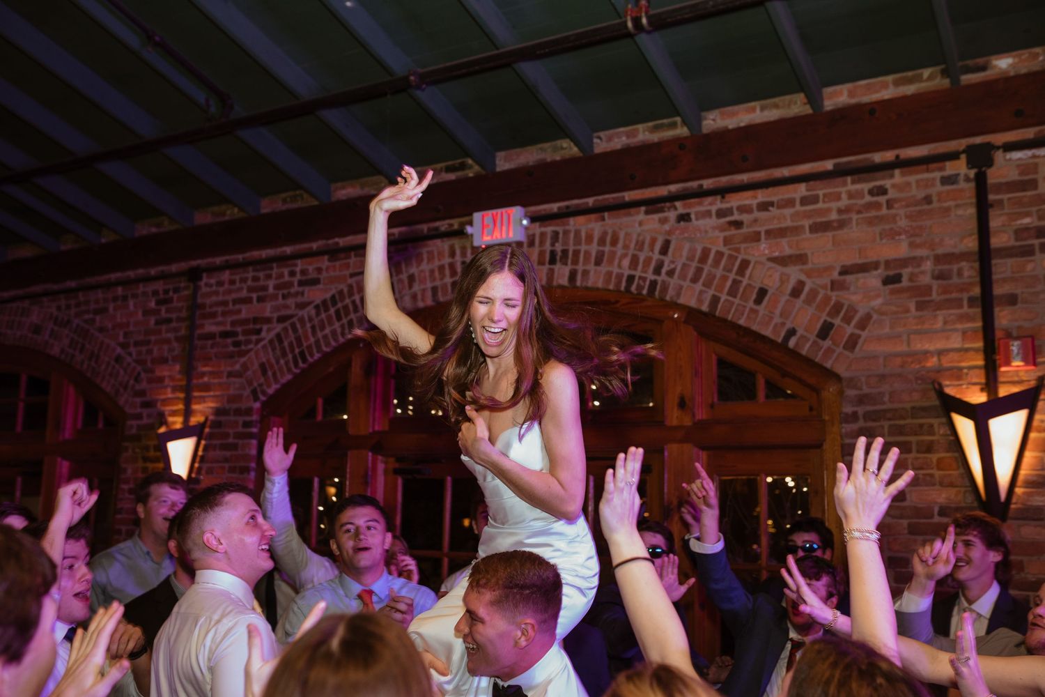 Bride celebrating at wedding reception, being lifted in the air by her friends.