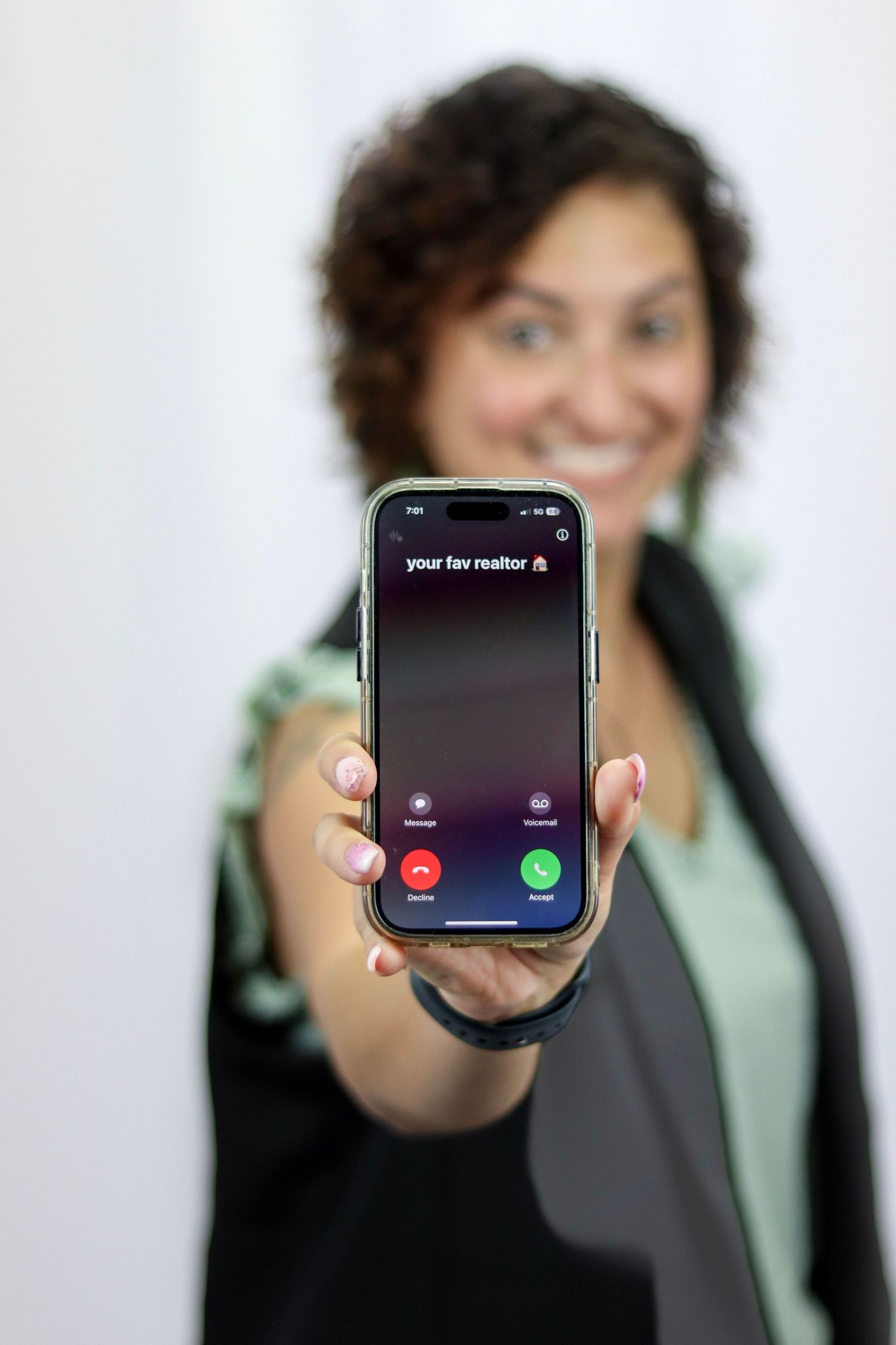 A female realtor holding their phone up to the camera that shows they are receiving a call.