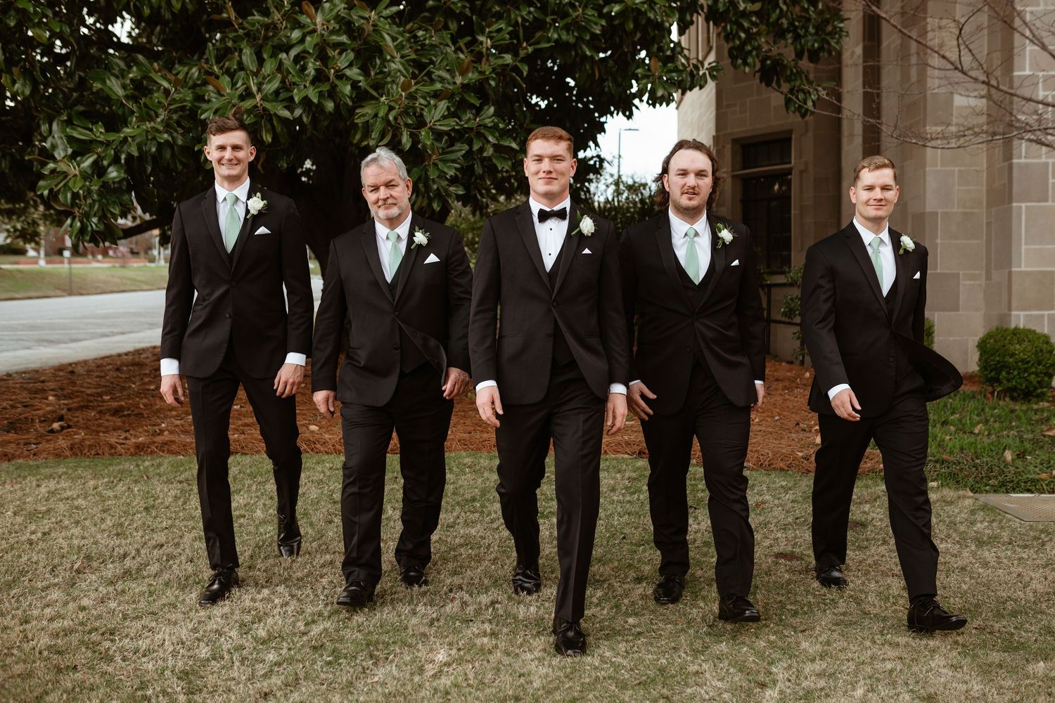 Groom and groomsmen walking together on wedding day.