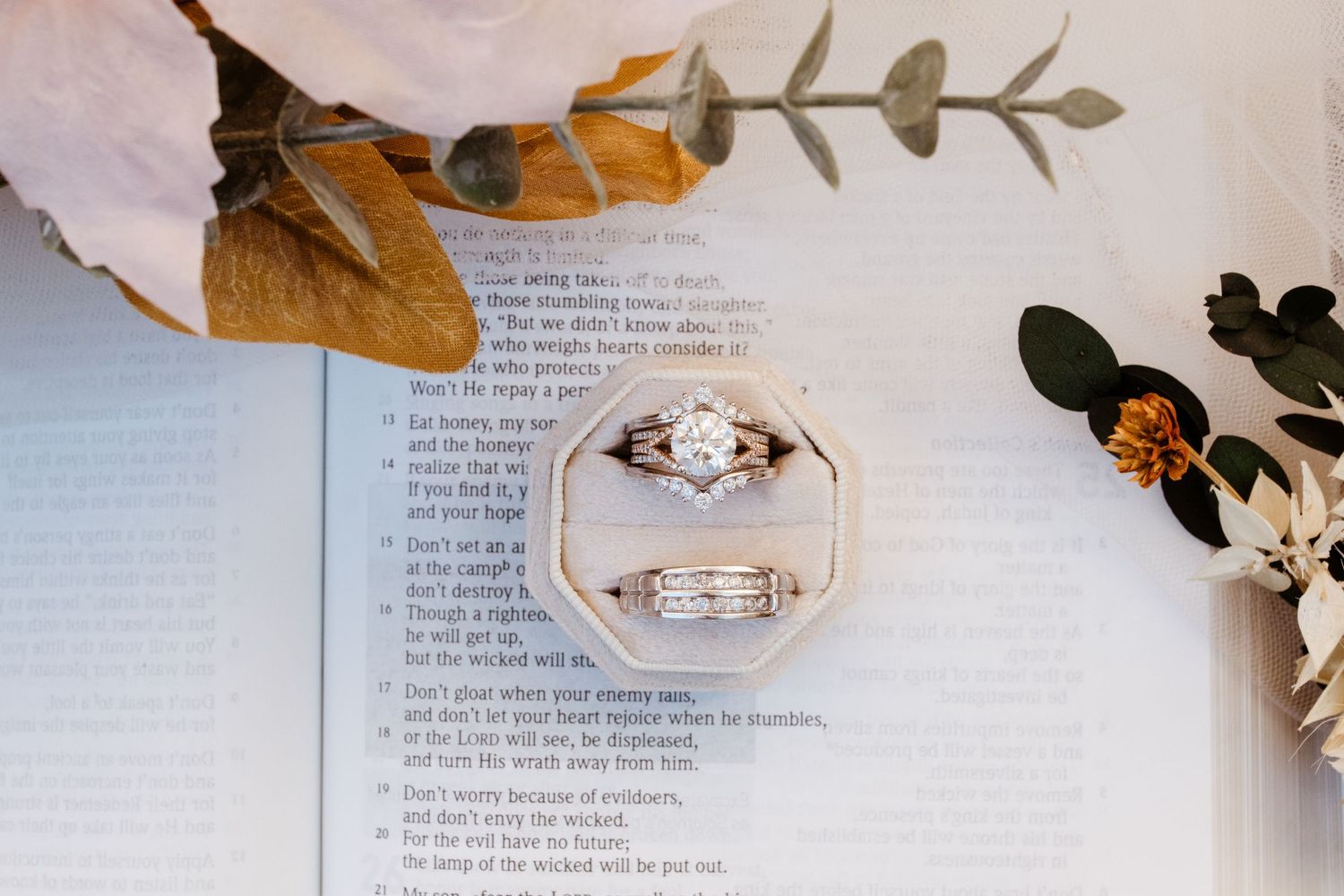 Wedding ring detail photo with flowers on top of open bible.