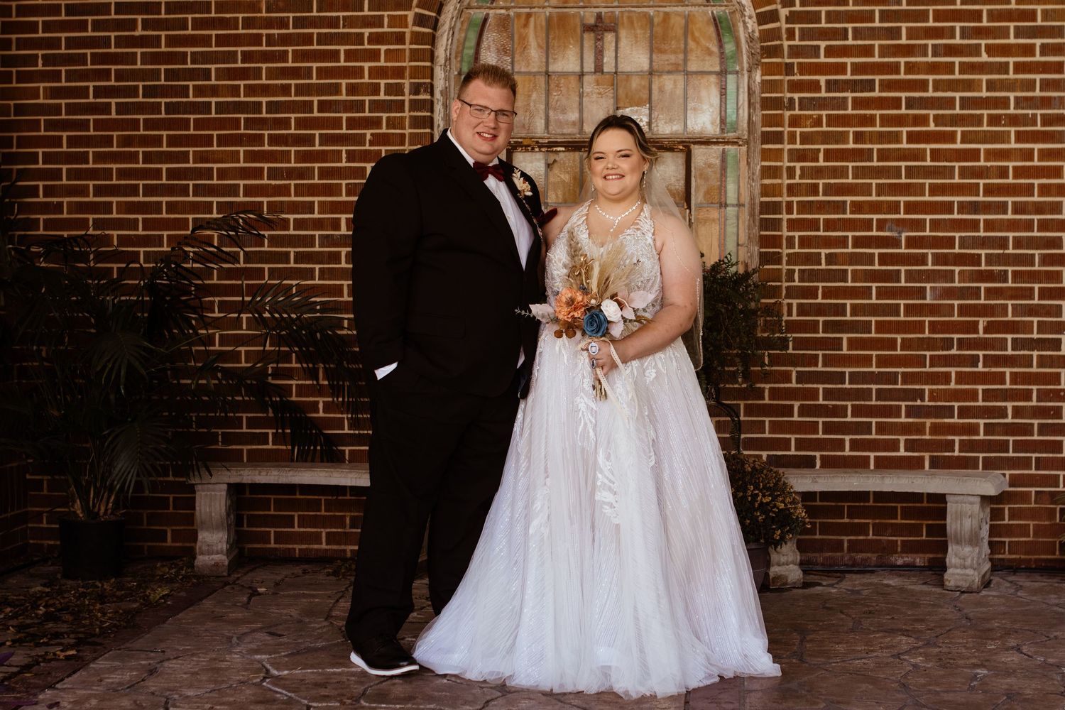 Picture of a couple on their wedding day against a brick wall.