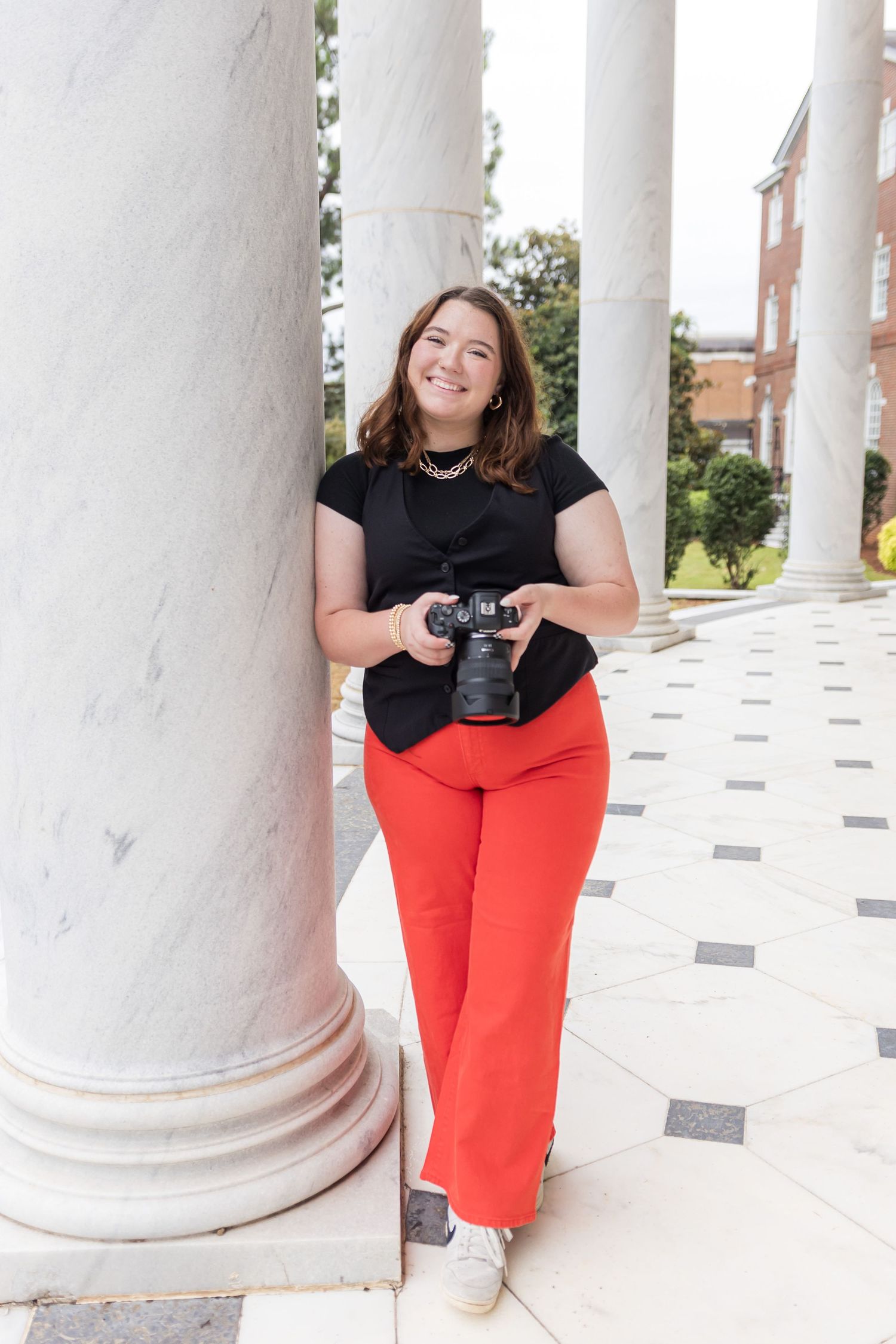 Photographer standing on marble ground holding their camera.