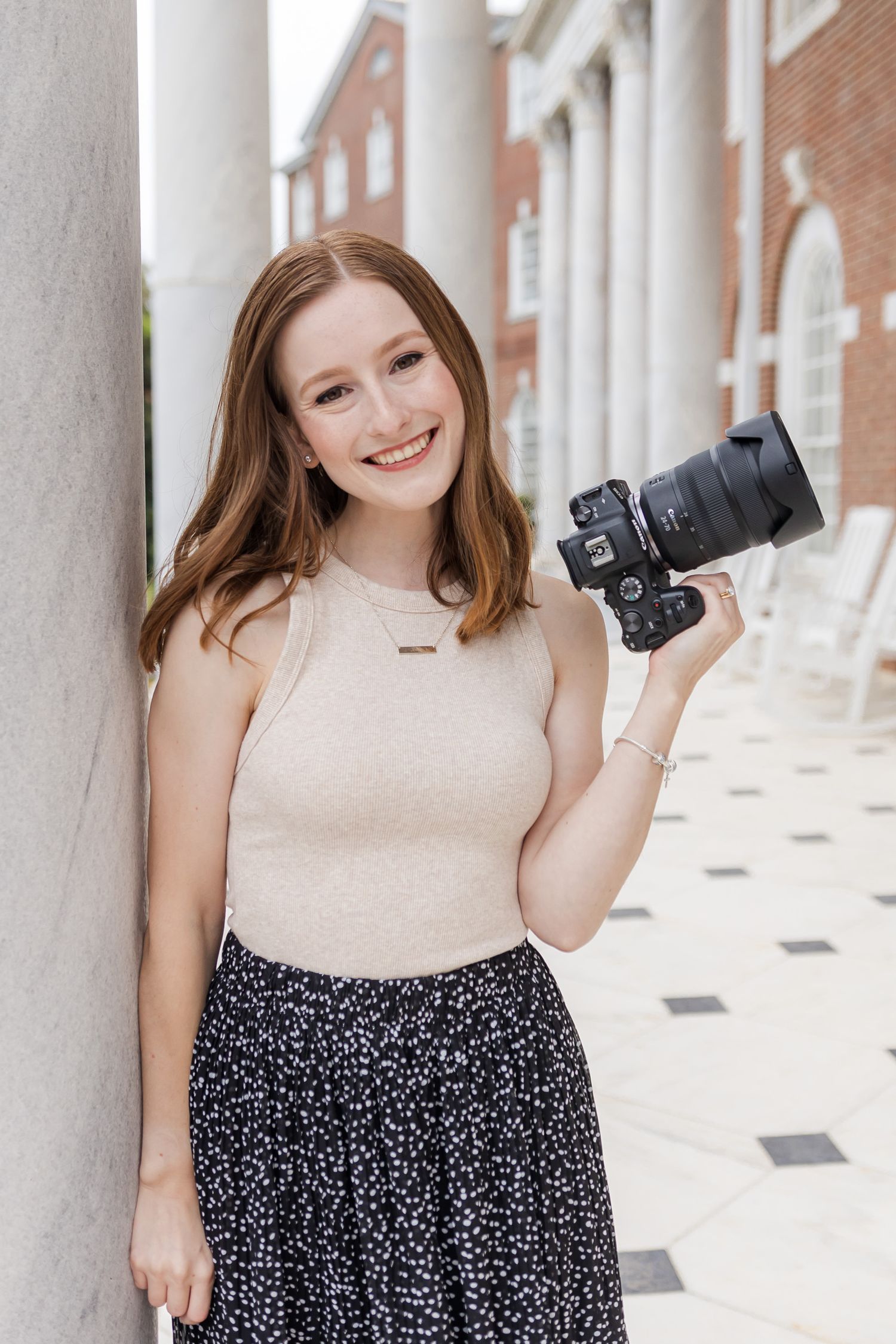 Photographer Sarah Frady in Macon, Georgia holding her camera and leaning against a white marble column.