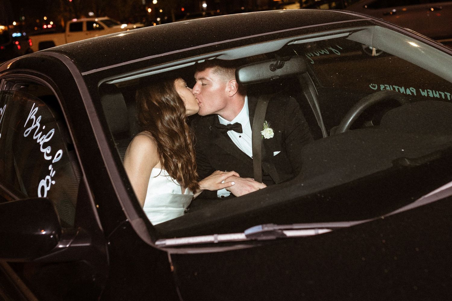 Bride and groom kissing in the getaway car on their wedding day.