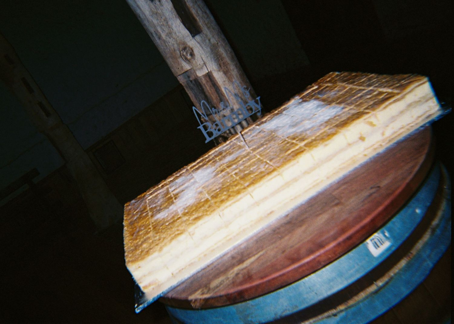 Close-up of a rustic wooden board resting on a wine barrel in a dimly lit cellar.