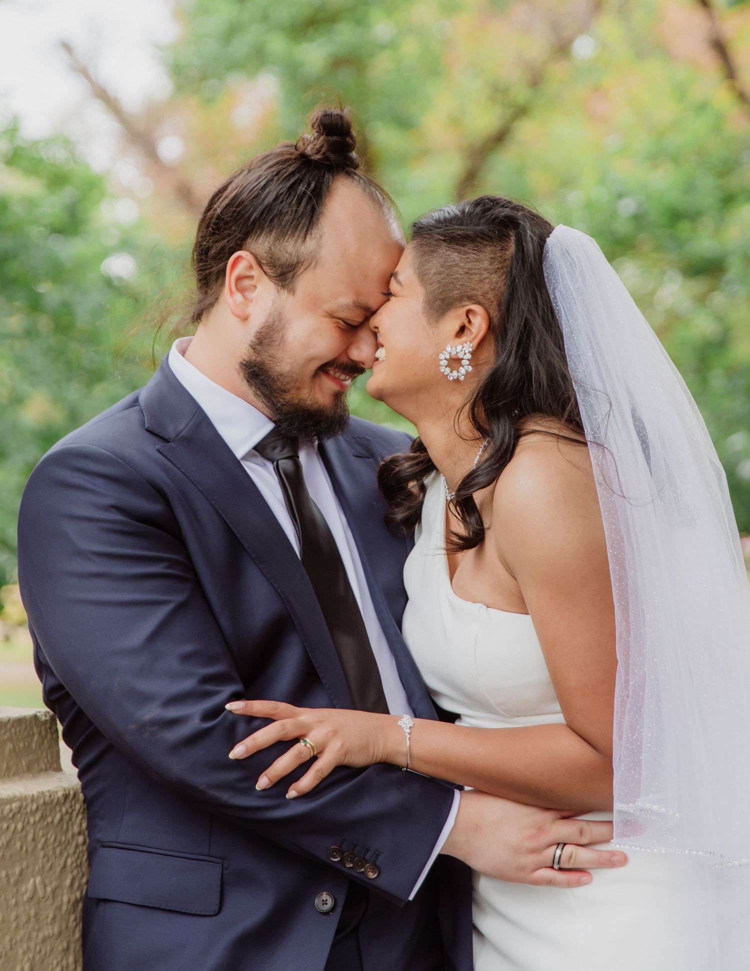 Bride and groom share an intimate forehead-to-forehead moment outdoors on their wedding day.