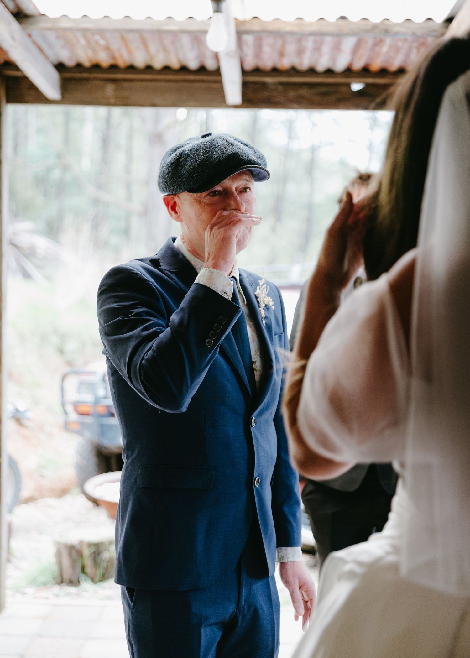 Emotional father wiping tears while seeing his daughter in her wedding dress for the first time.