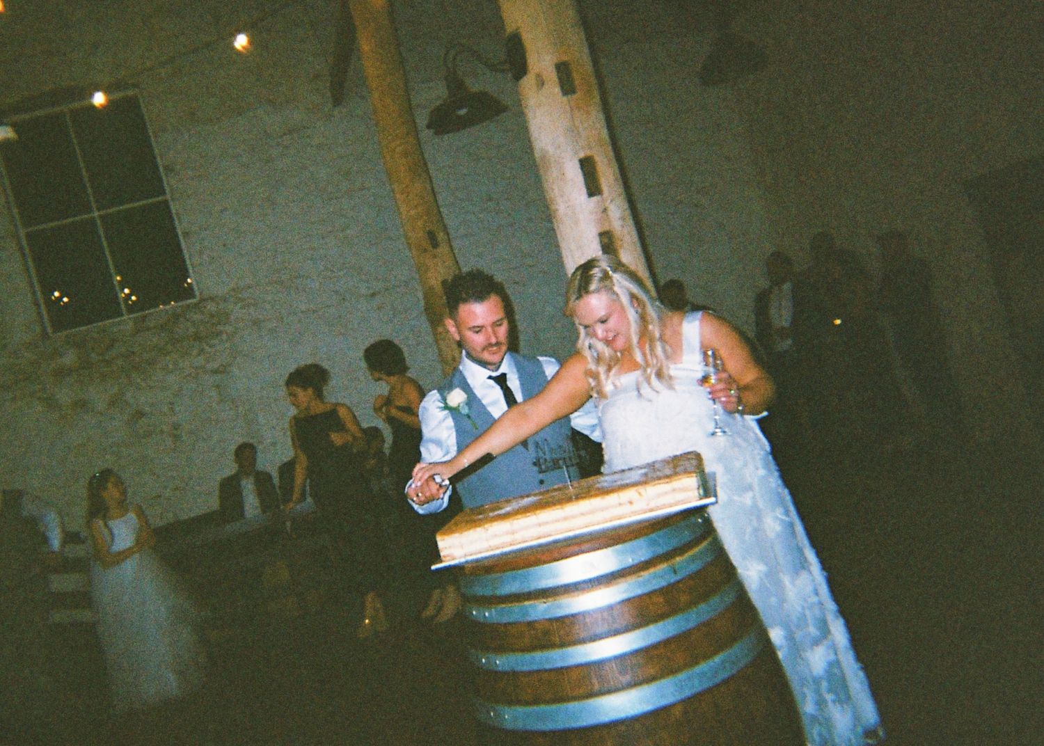 Bride and groom cutting their wedding cake placed on top of a wooden wine barrel.