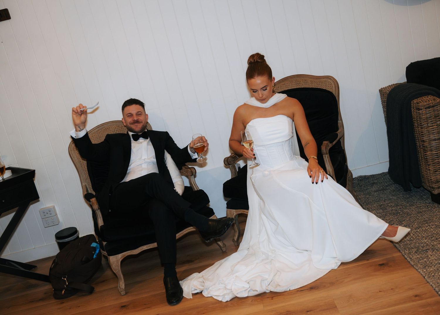 Bride and groom celebrating joyfully in chairs at wedding reception.