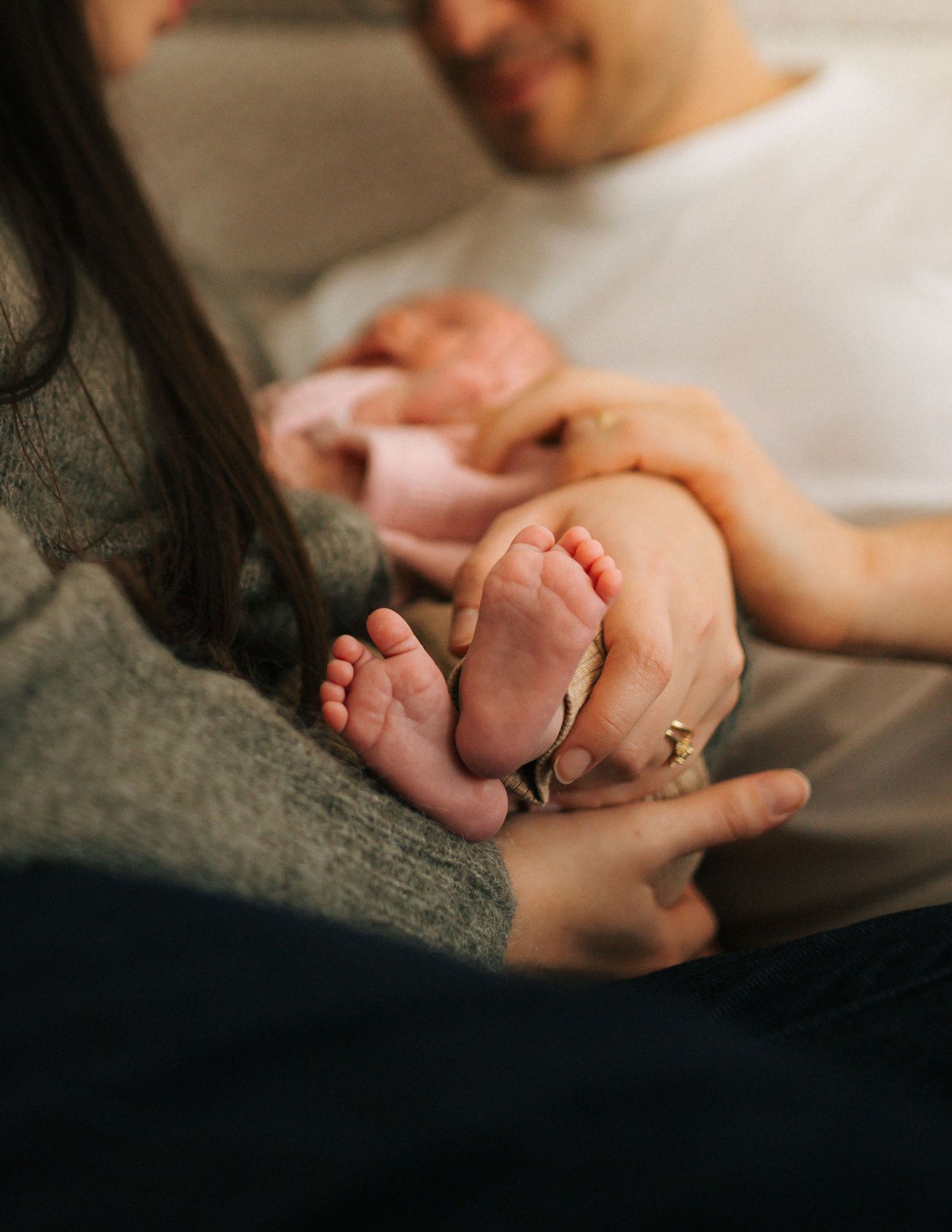 Parents gently holding their newborn baby tiny feet together in a warm intimate moment.