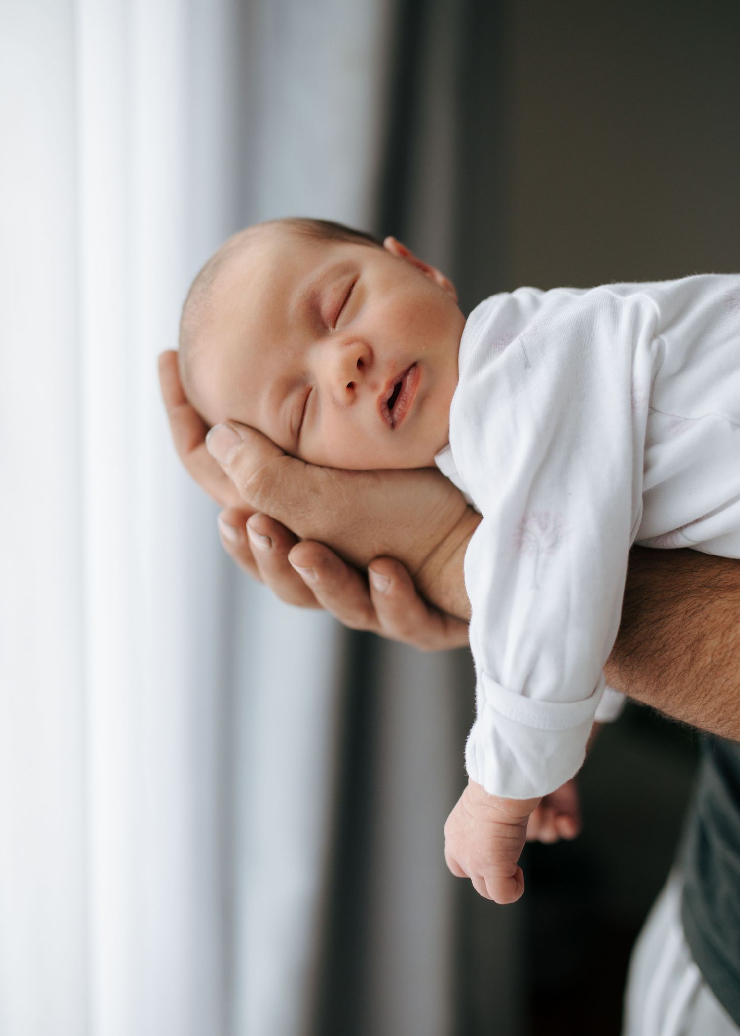Close-up of peaceful sleeping newborn cradled in parent's supportive hand.