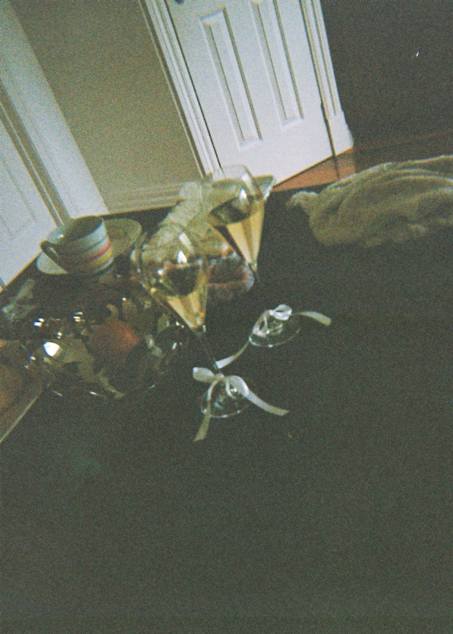 Wedding reception glassware and decorative items arranged on a dark surface near a white door.