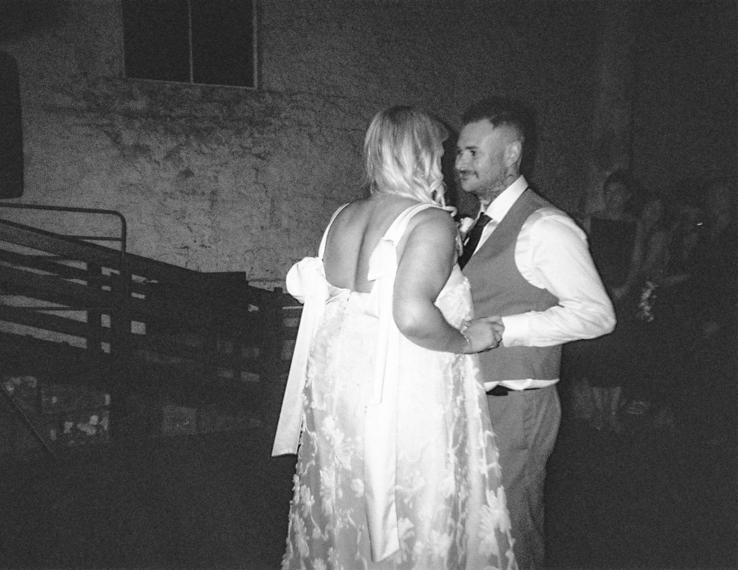 Bride and groom sharing their first dance in black and white at a rustic wedding reception venue.