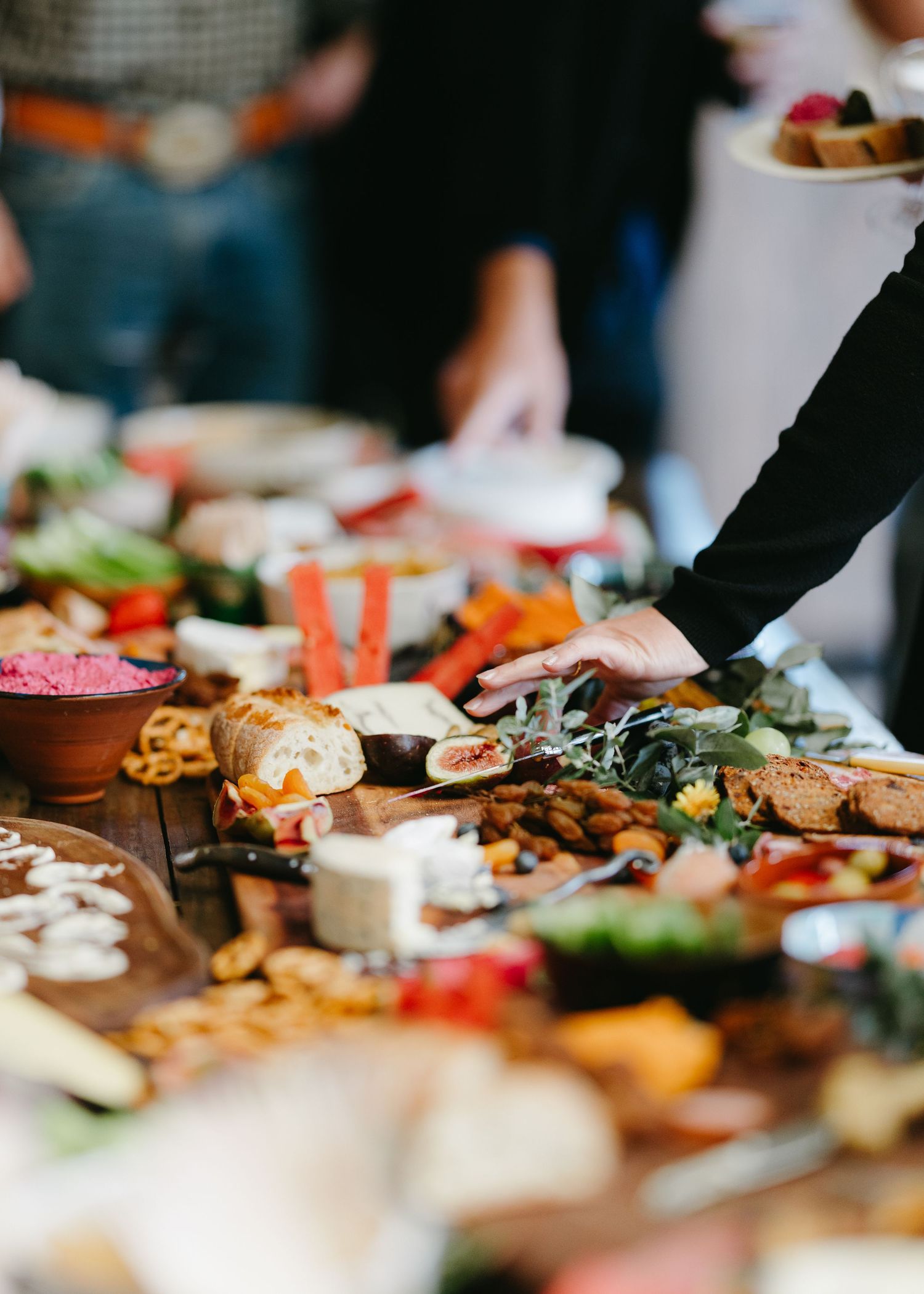 A lavish grazing board with cheeses, vegetables, bread, and dips at a wedding reception.