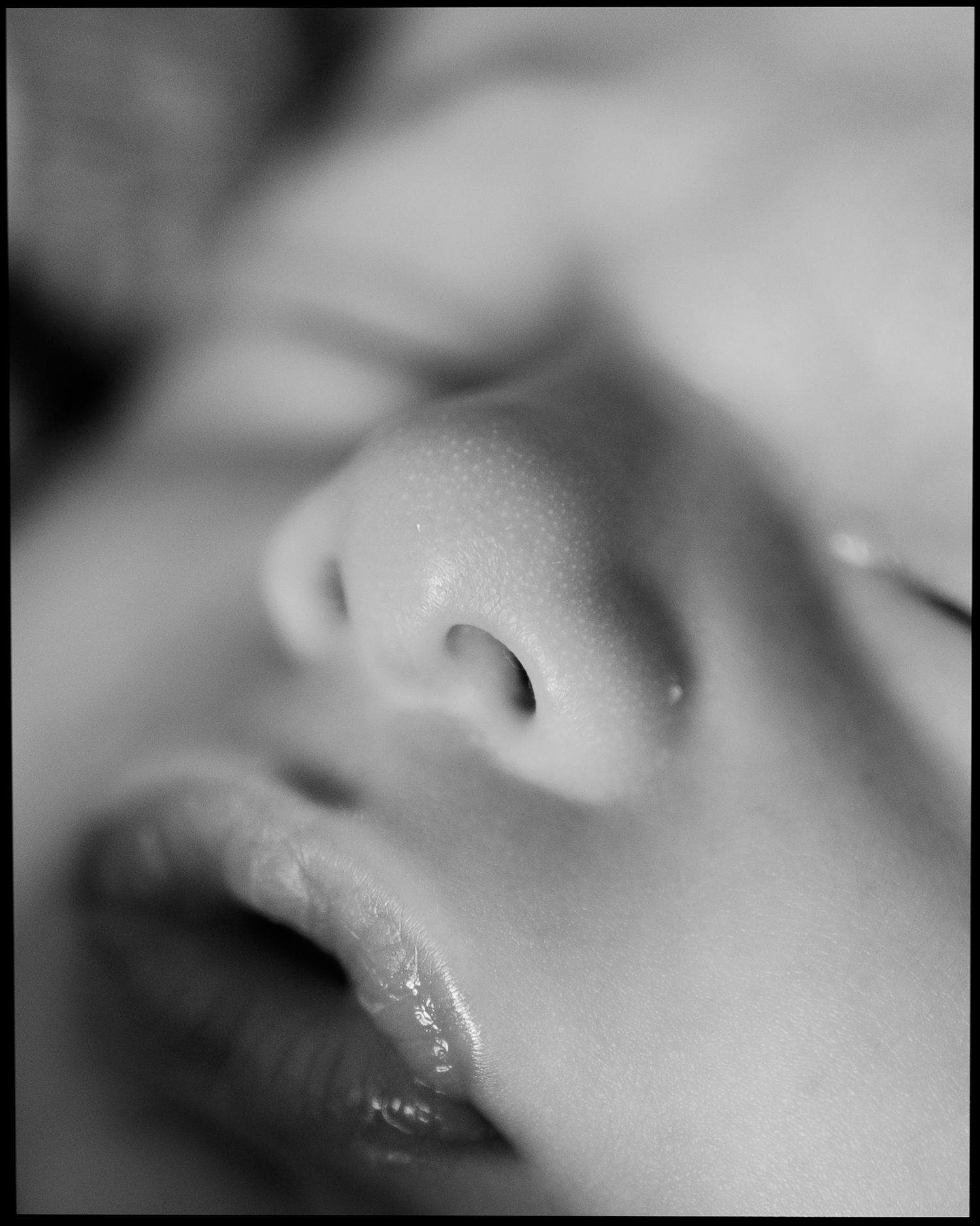 Black and white close-up macro photo of a sleeping newborn baby's face.