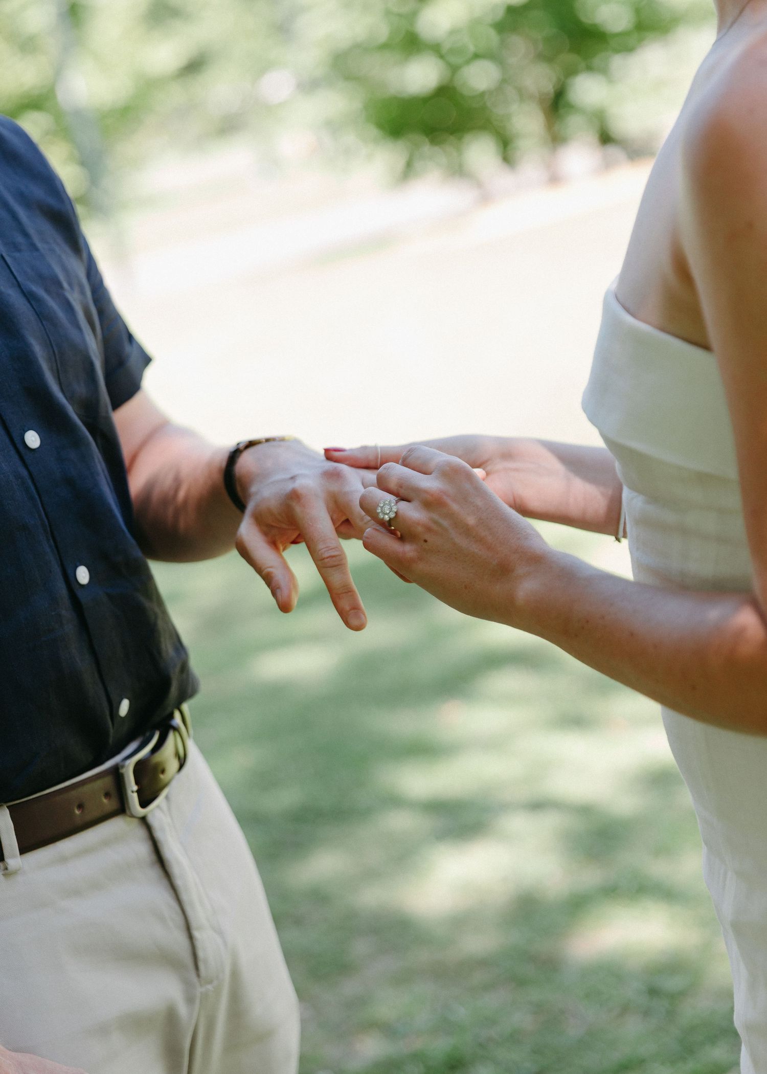Bride places wedding ring on grooms hand during intimate outdoor wedding ceremony.