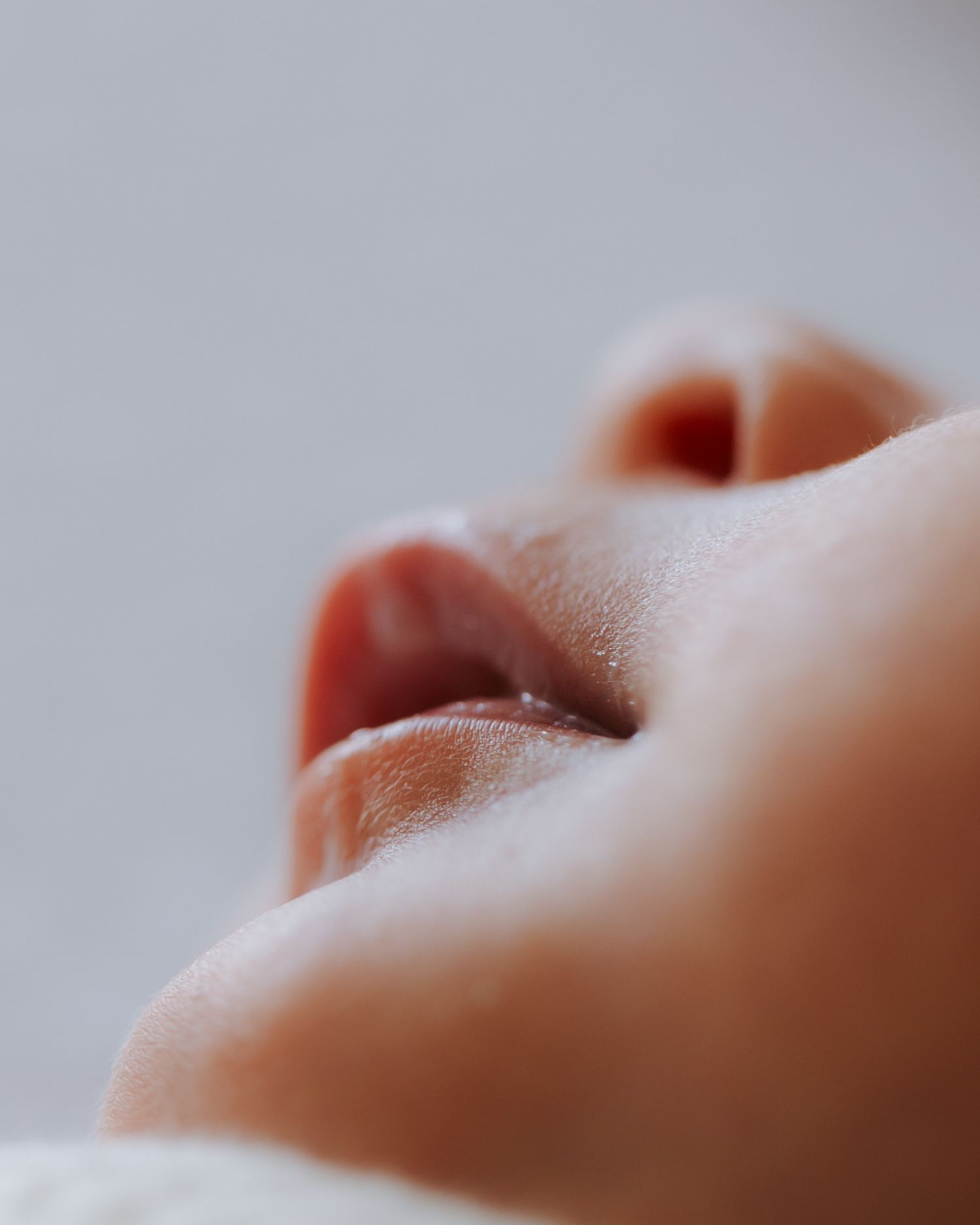 Soft close-up macro photograph of a newborn baby's delicate lips and nose.