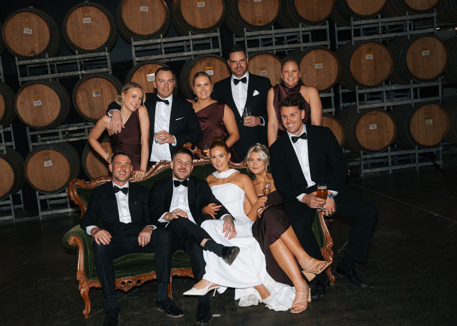 Bridal party group photo inside rustic winery barrel room after wedding ceremony.