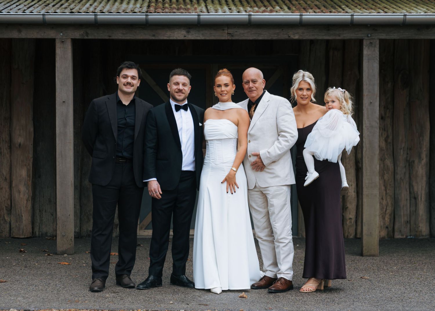Family portrait with bride and groom at rustic barn wedding venue.