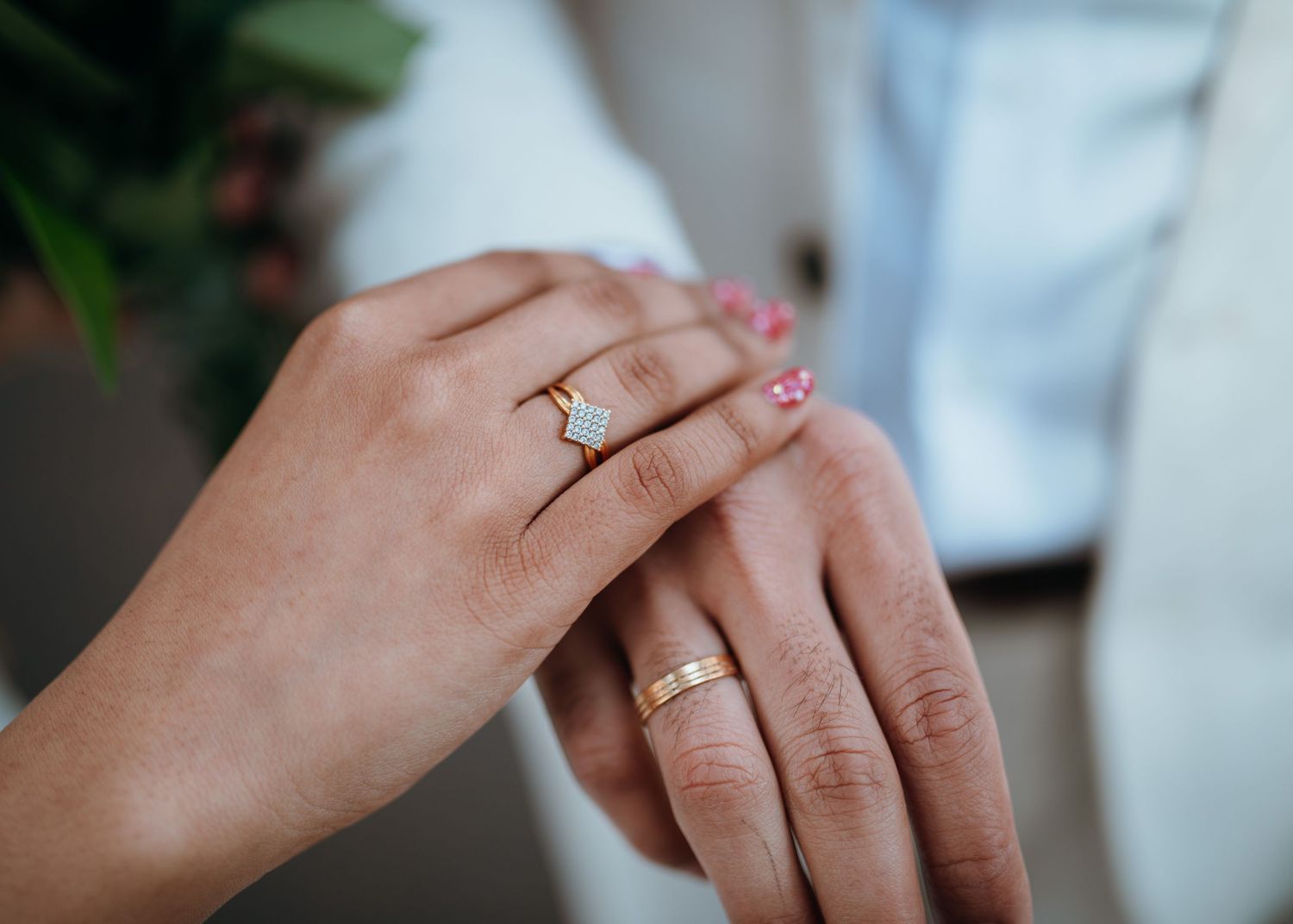 Close-up of bride and groom hands showing gold wedding bands and elegant diamond engagement ring after ceremony.
