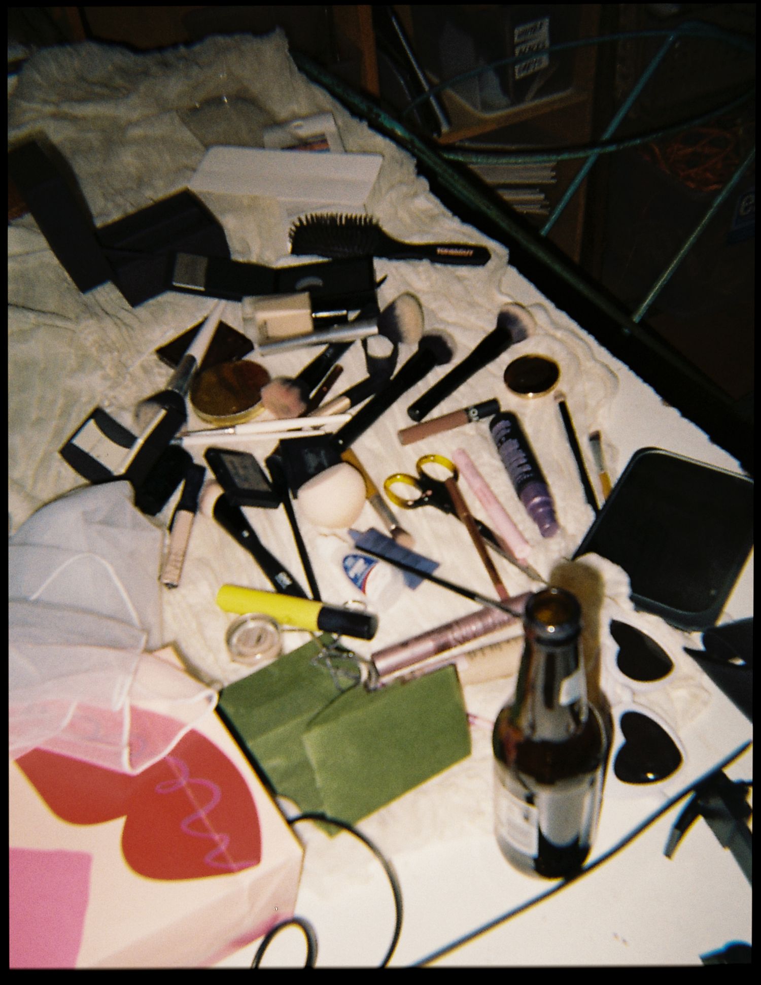 Cluttered wedding preparation table covered with makeup brushes, cosmetics, scissors, and beauty accessories.