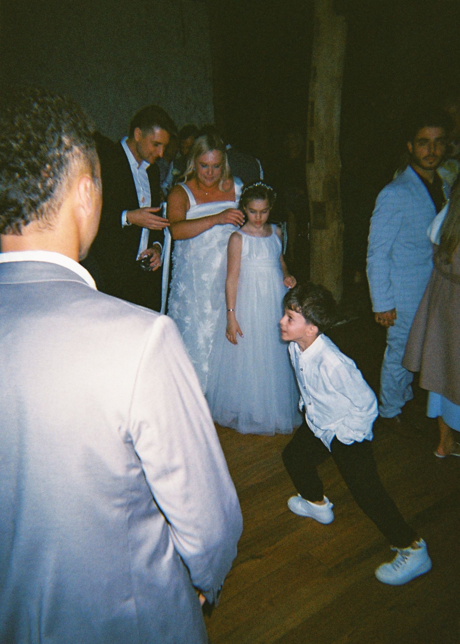 Bride dancing with children including a flower girl and ring bearer at a lively wedding reception celebration.