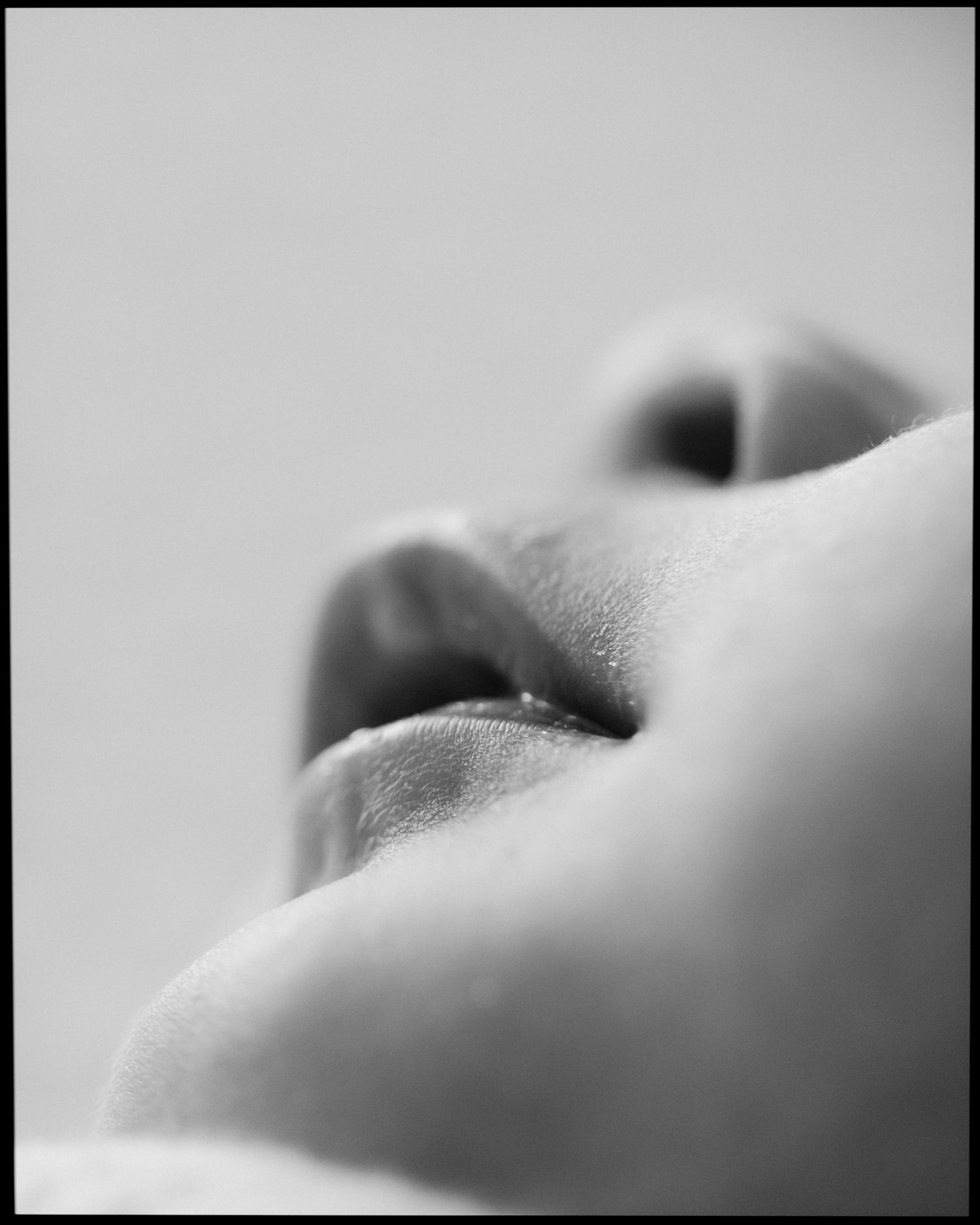 Black and white macro close-up of a newborn baby's delicate lips and nose.