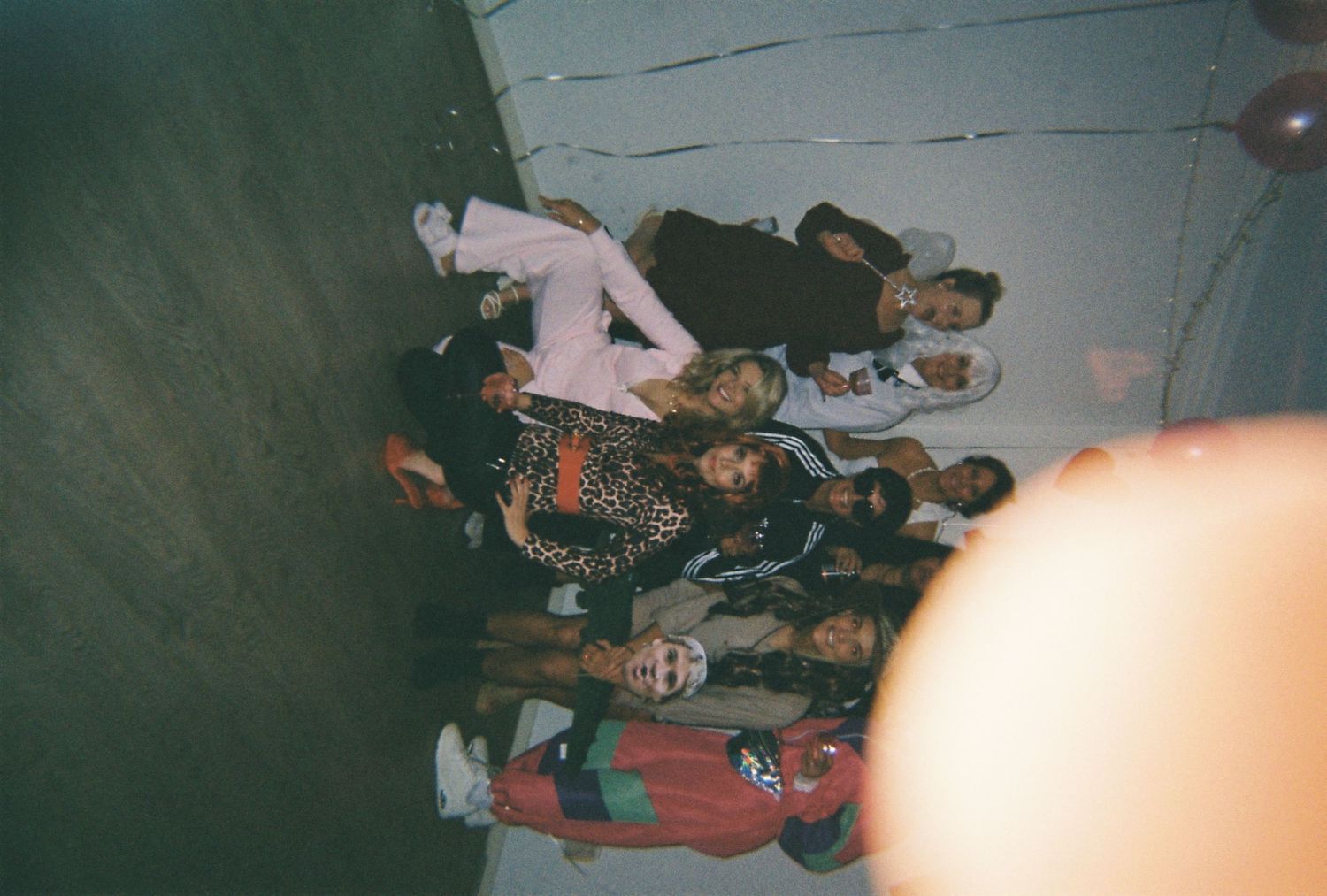 A group of friends in costumes pose together at an indoor Halloween party, photographed from above.