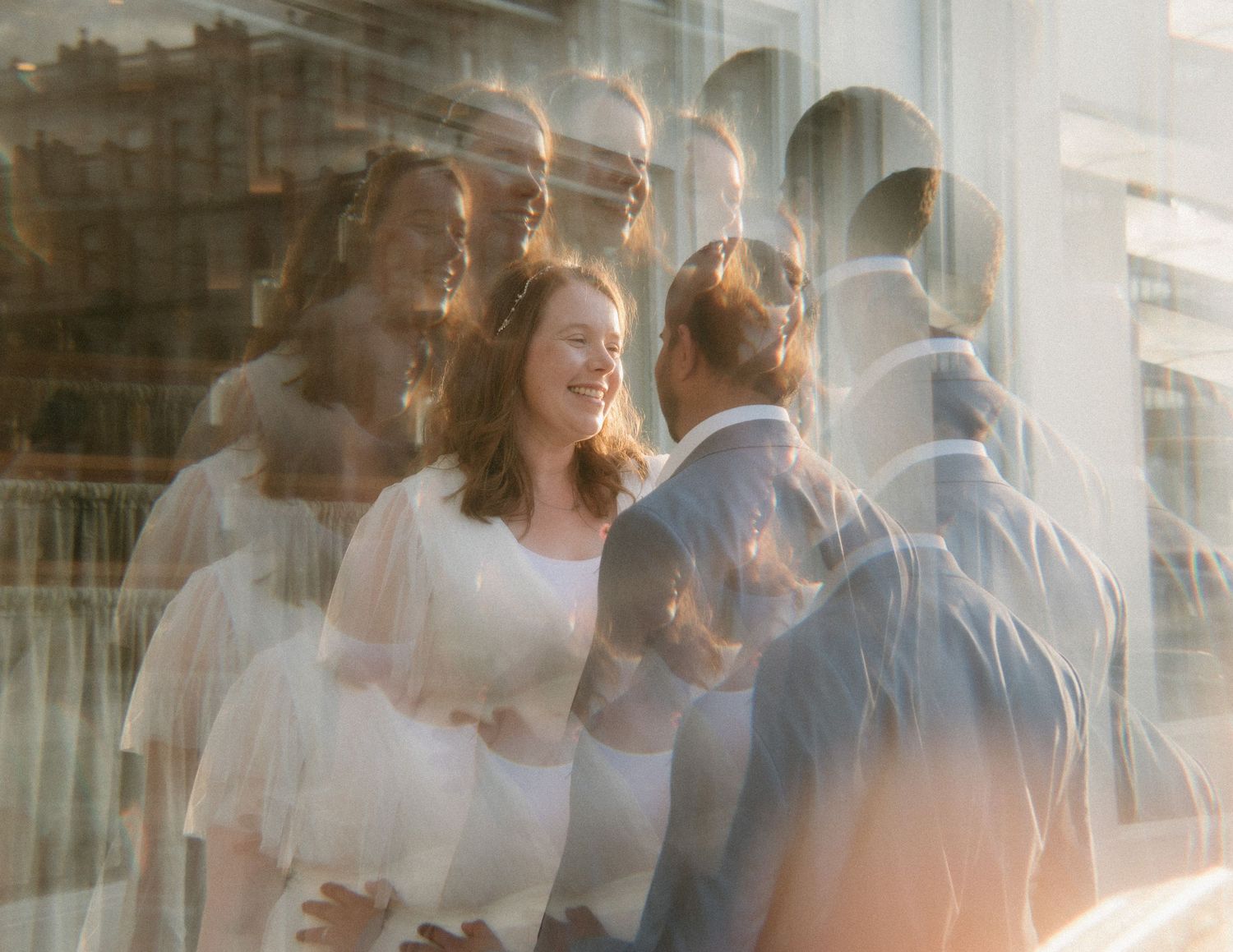 Artistic multi-exposure portrait of bride and groom sharing a moment in golden sunlight.