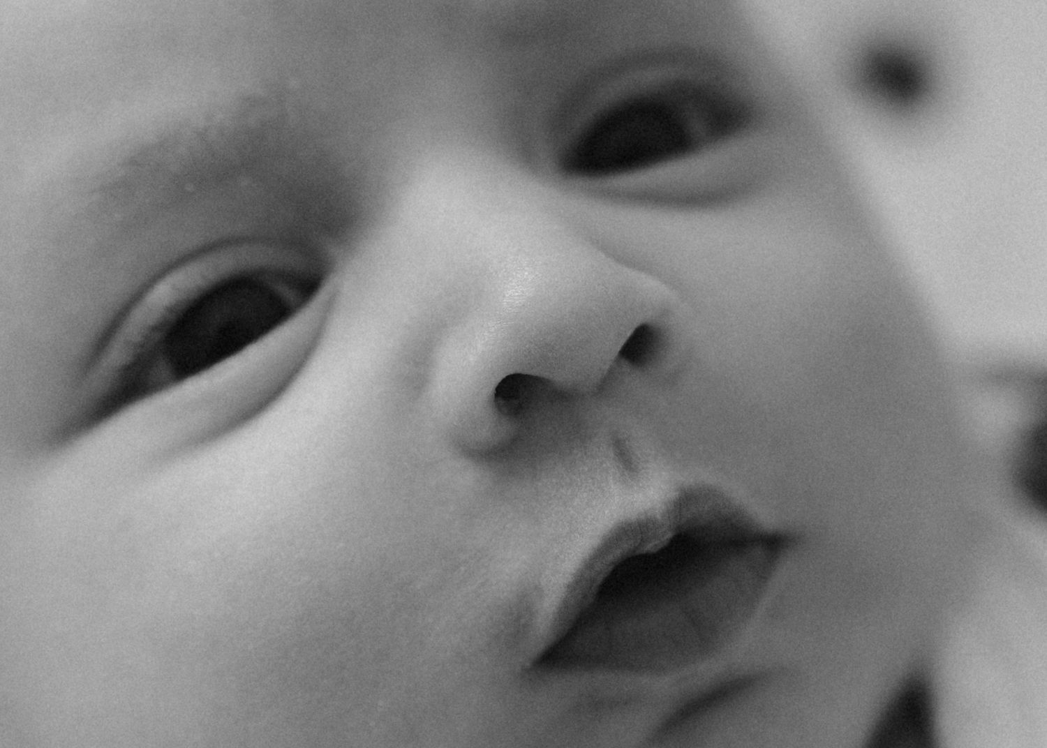Intimate black and white close-up portrait of a peaceful newborn baby face with soft features.
