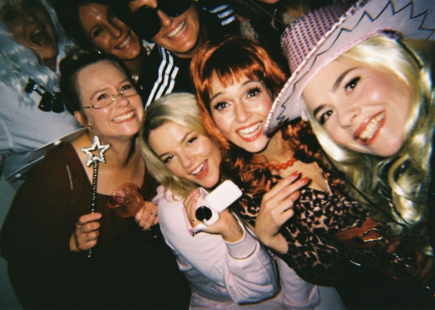 A group of women in costumes smile and pose together at a fun Halloween party.