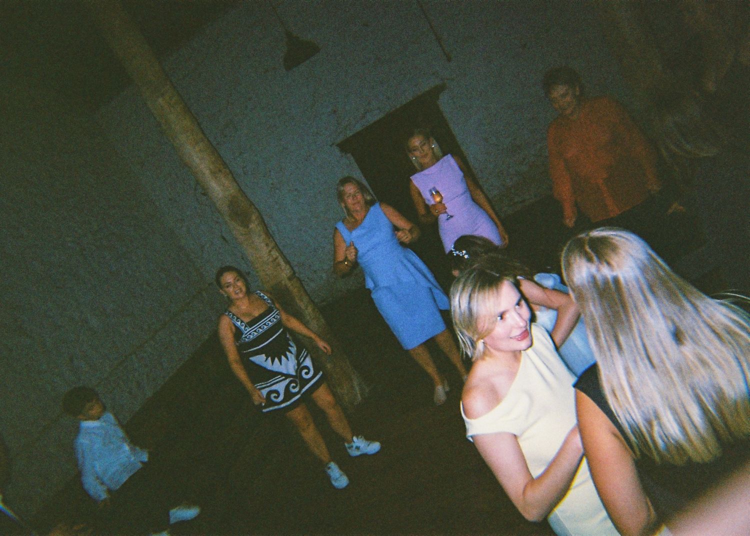 Guests dancing and socializing at an indoor wedding reception party in a rustic venue.