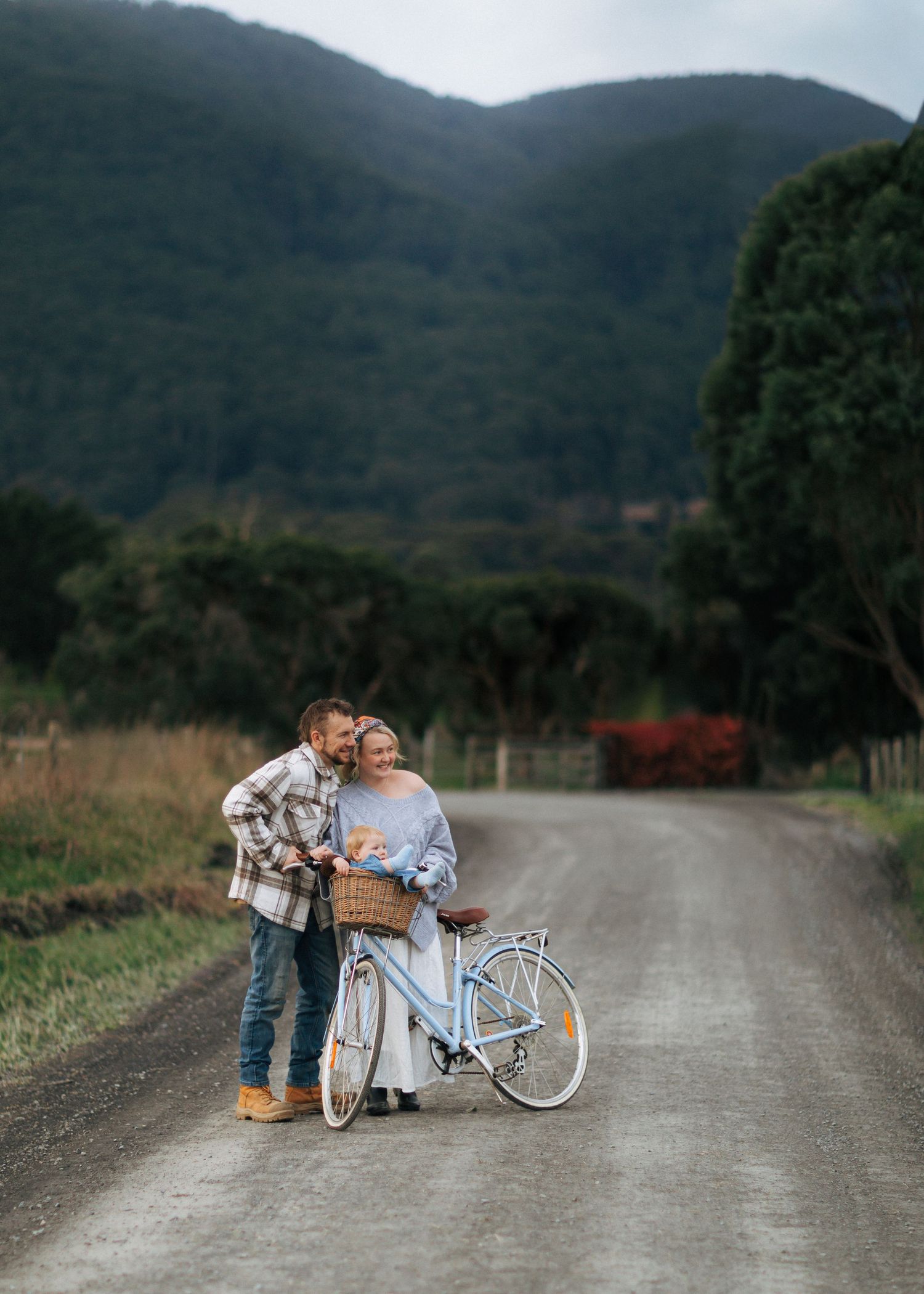 Romantic couple sharing a tender moment beside a vintage blue bicycle on a country road.