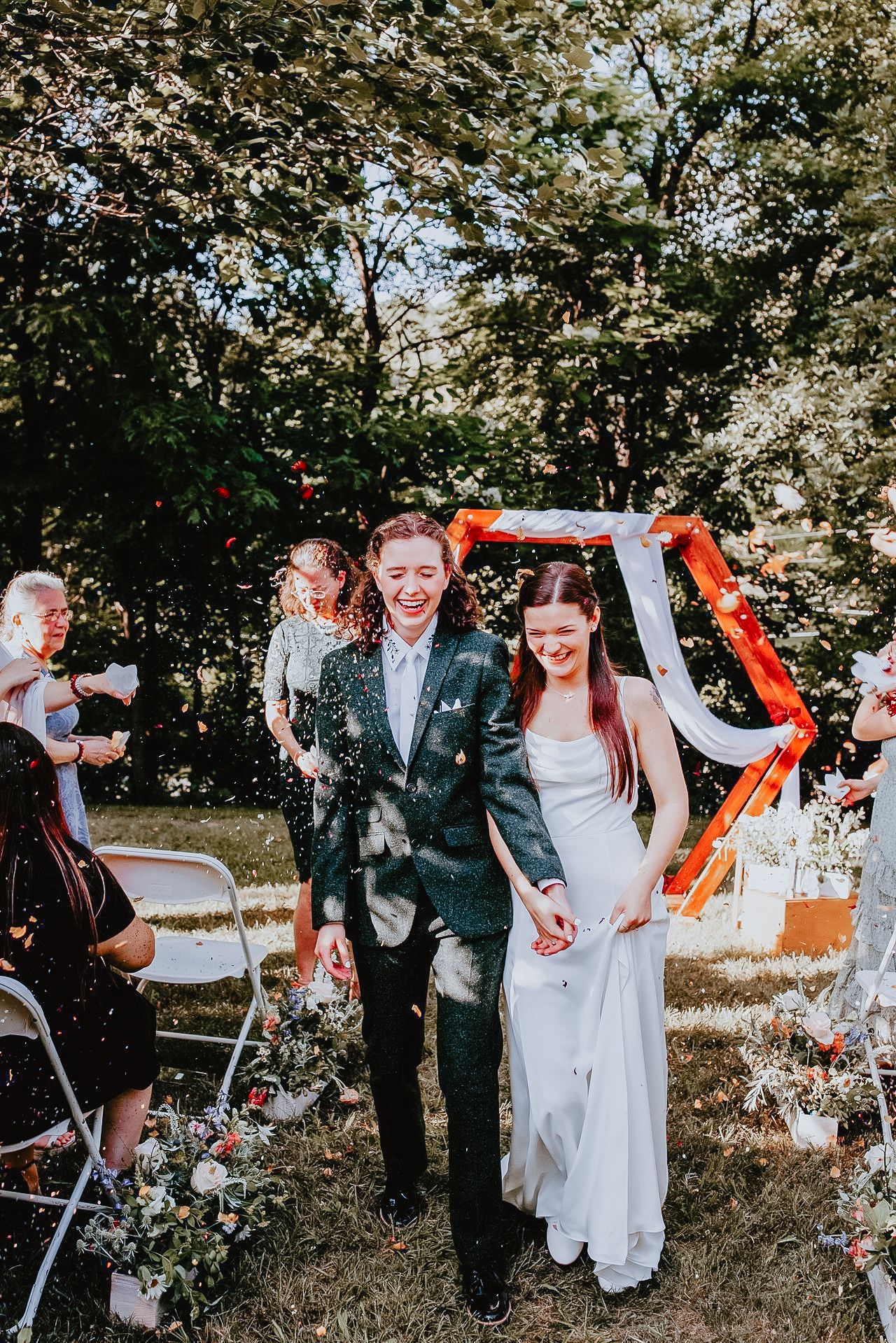 Two women walking down the aisle at their wedding with confetti being thrown in Allentown, Pennsylvania.