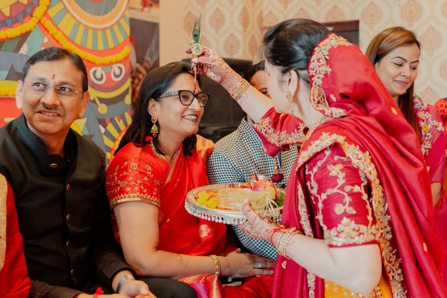 Indian bride in red saree performing traditional wedding ritual with family members during festive ceremony.