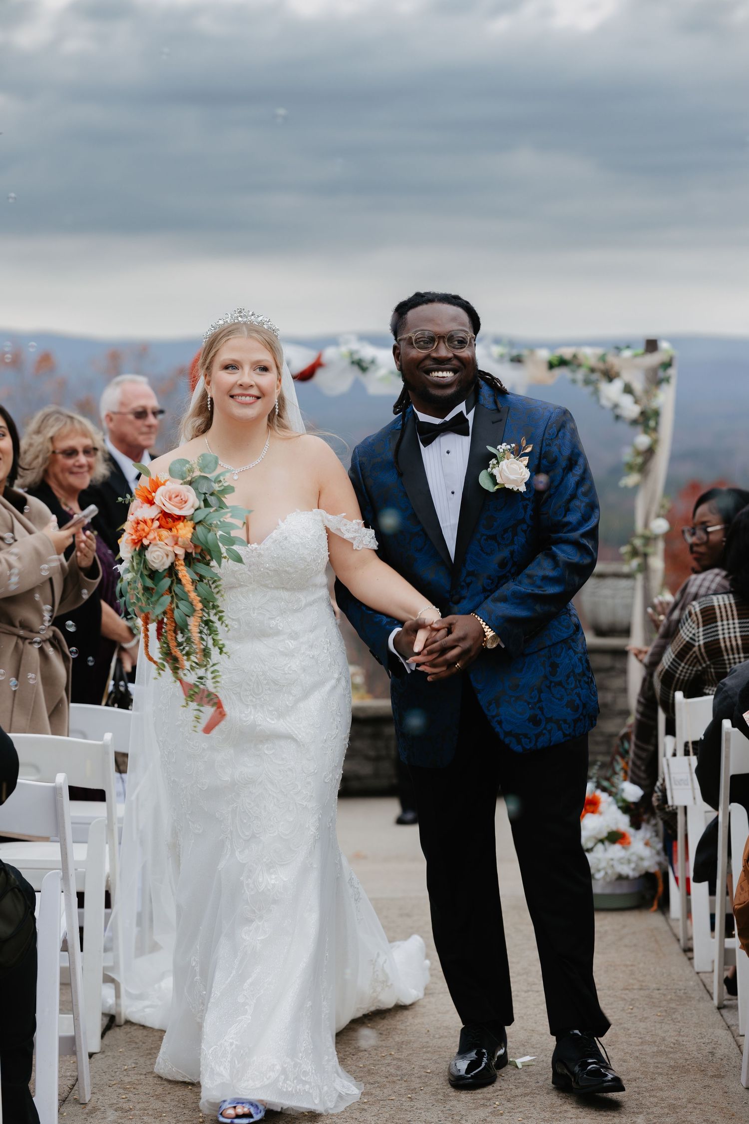 Newlywed couple walking down the aisle after wedding ceremony, bride in lace gown with orange bouquet. Film Wedding Photography in PA