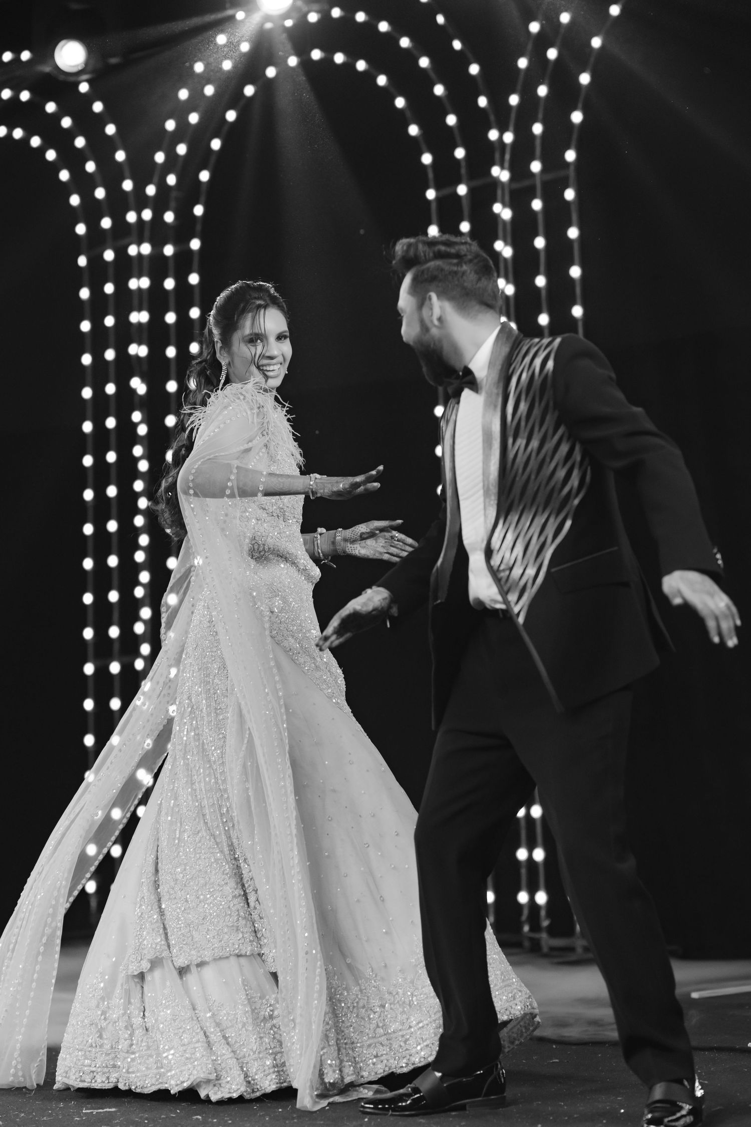 Bride and groom dancing on a decorated stage in black and white wedding photo.