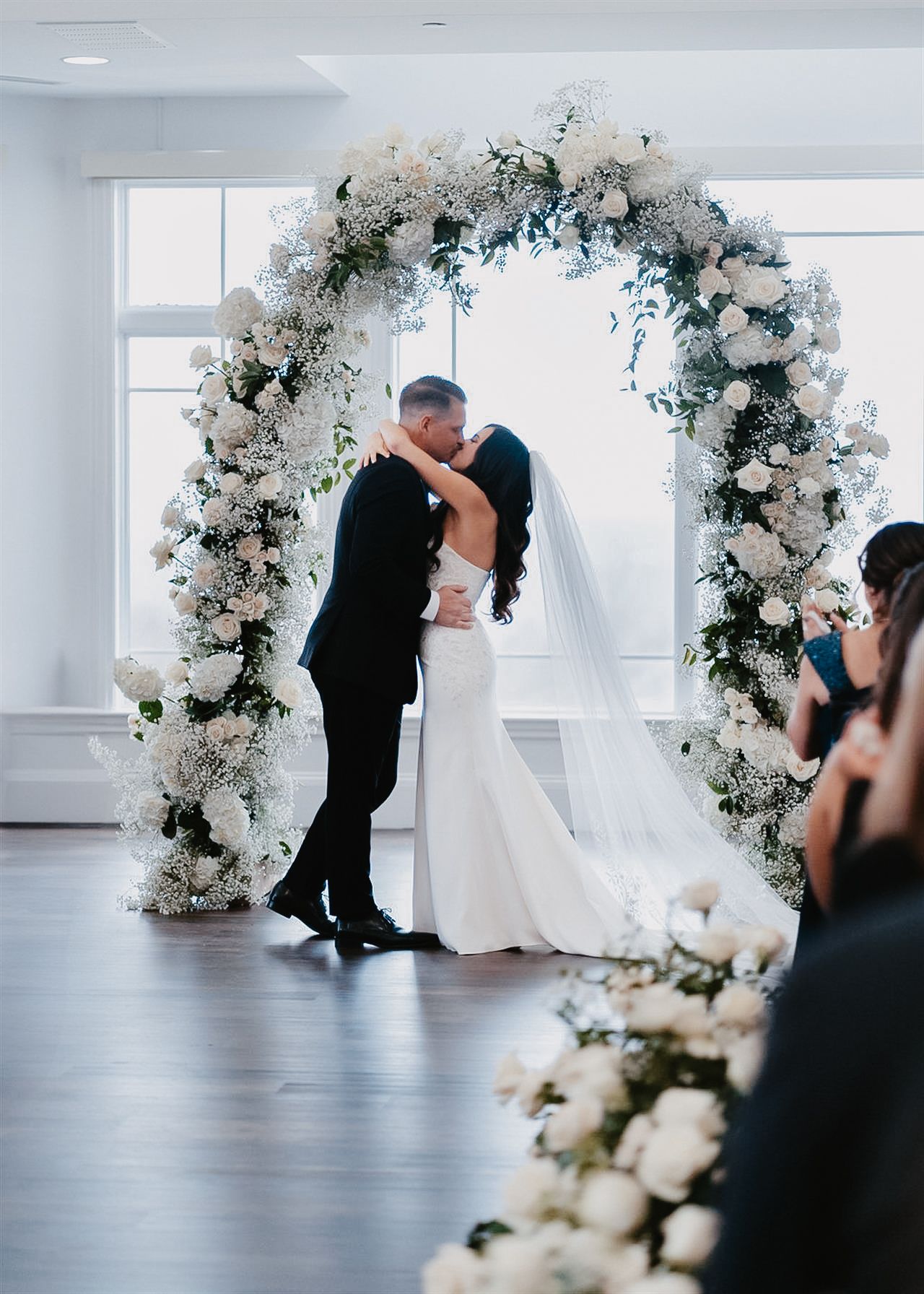 Refined indoor ceremony at high-end Lehigh Valley venue, featuring lush florals, soft sunlight, and the couple framed in airy elegance.