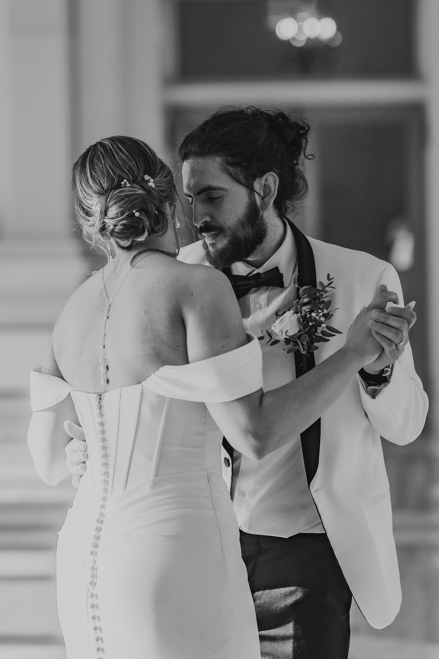 Black and white photo of a bride and groom sharing their first dance, groom in white tuxedo. Steven's School Ballroom Wedding Photography