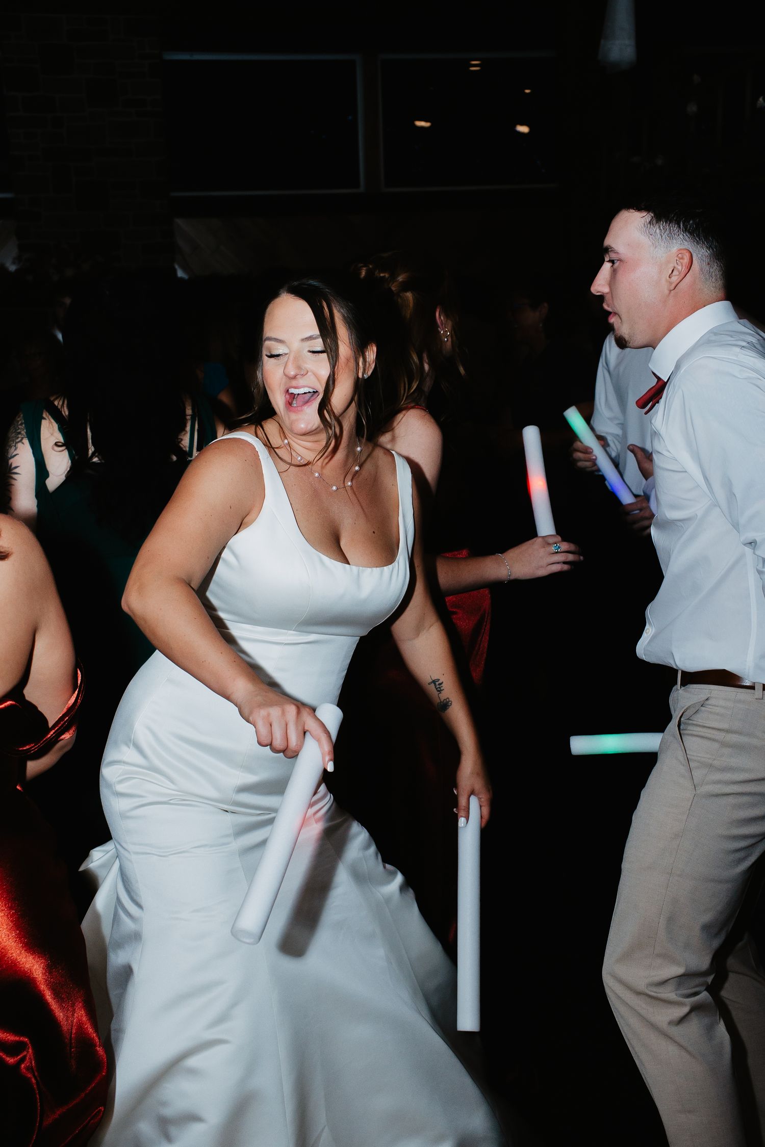 Bride in white gown dancing joyfully with glow sticks at wedding reception party in Bucks Country PA