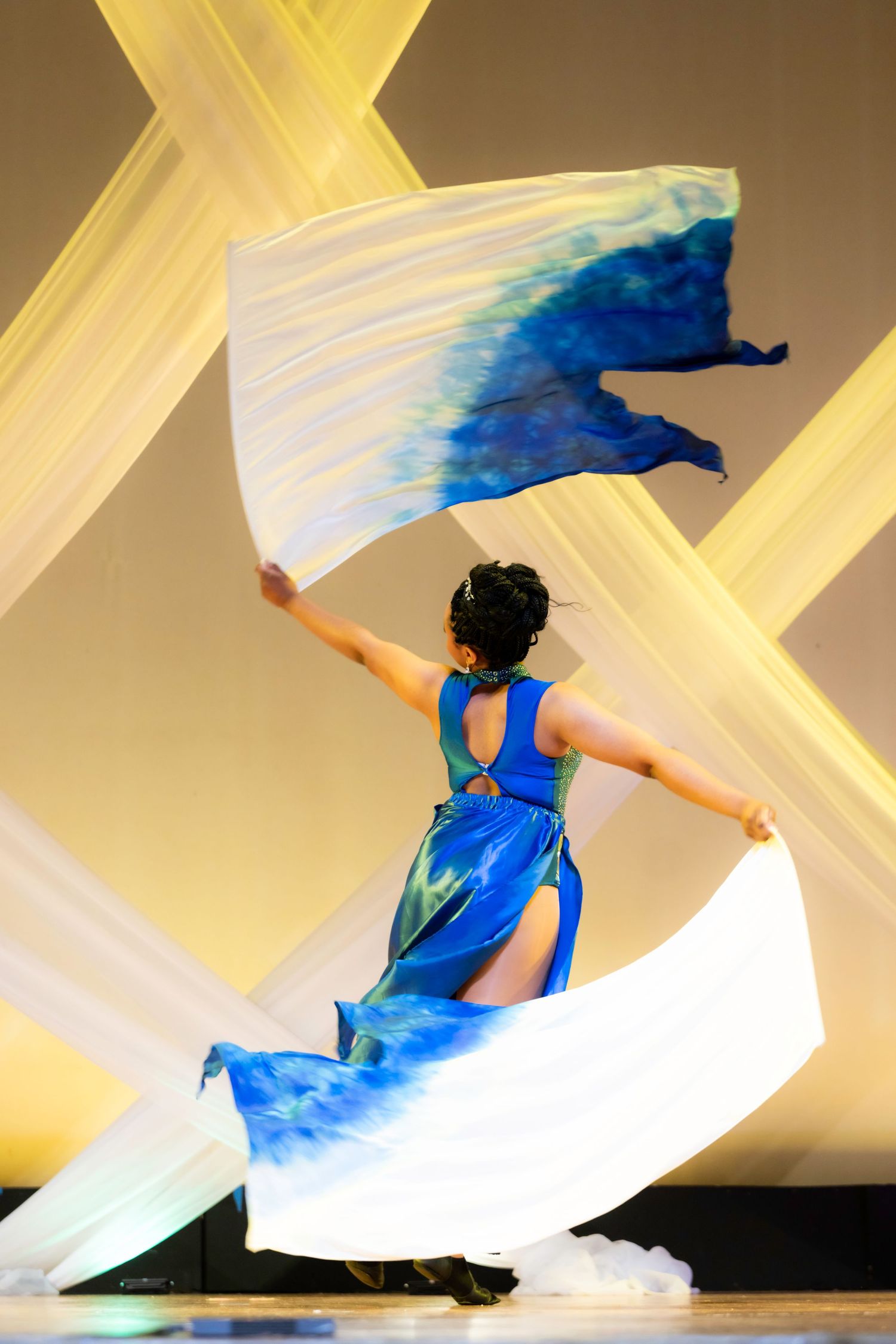 Dancer in blue and white dress waving silk fans on stage during a graceful Chinese cultural performance.
