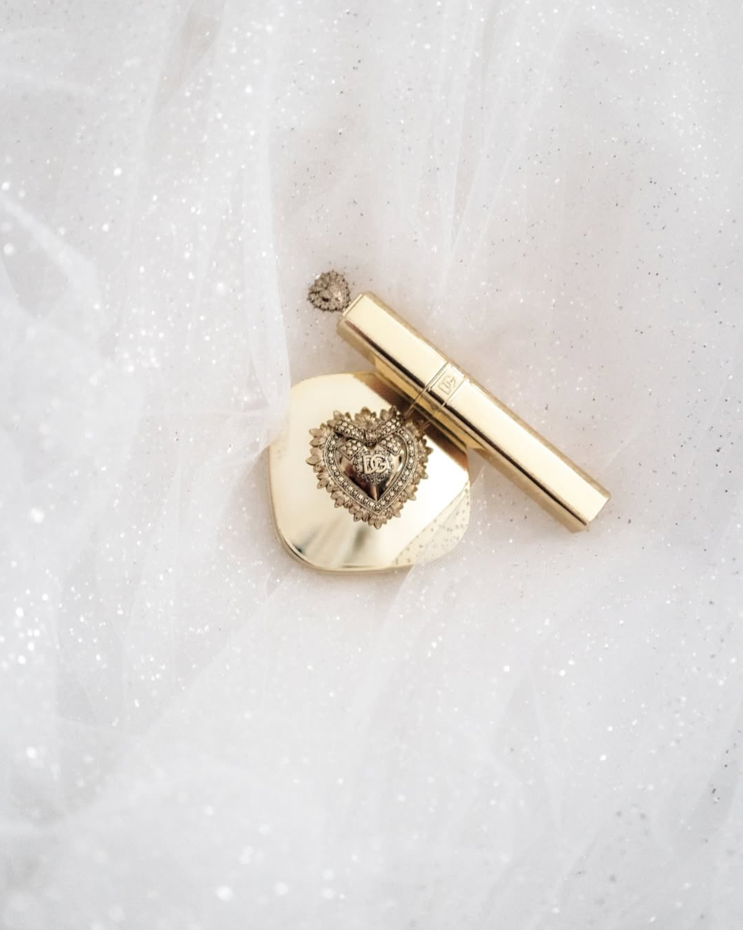 Delicate gold and crystal jewelry pieces arranged on white textured fabric.
