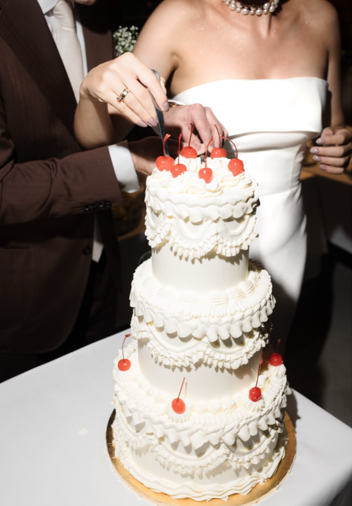 Wedding cake cutting sequence showing traditional white tiered cake with red cherry decorations.