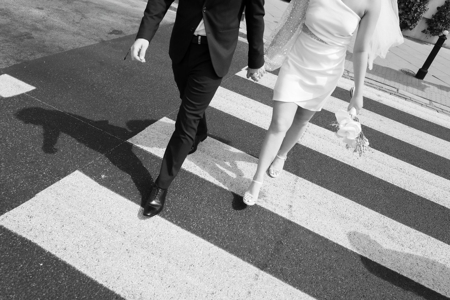 Black and white photo of couple walking across zebra crossing.
