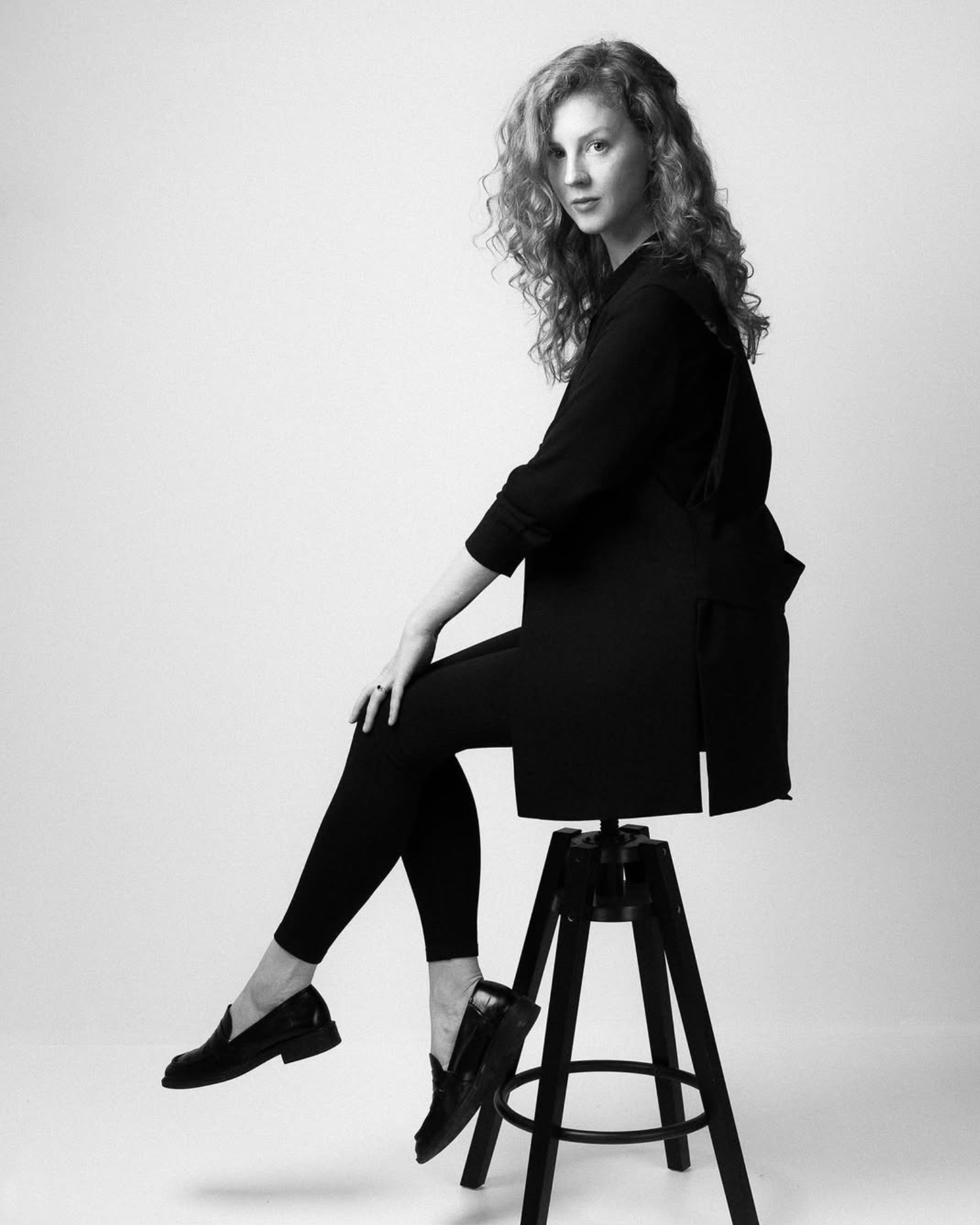 Artistic black and white fashion portraits showing poses on a minimalist stool against white backdrop.