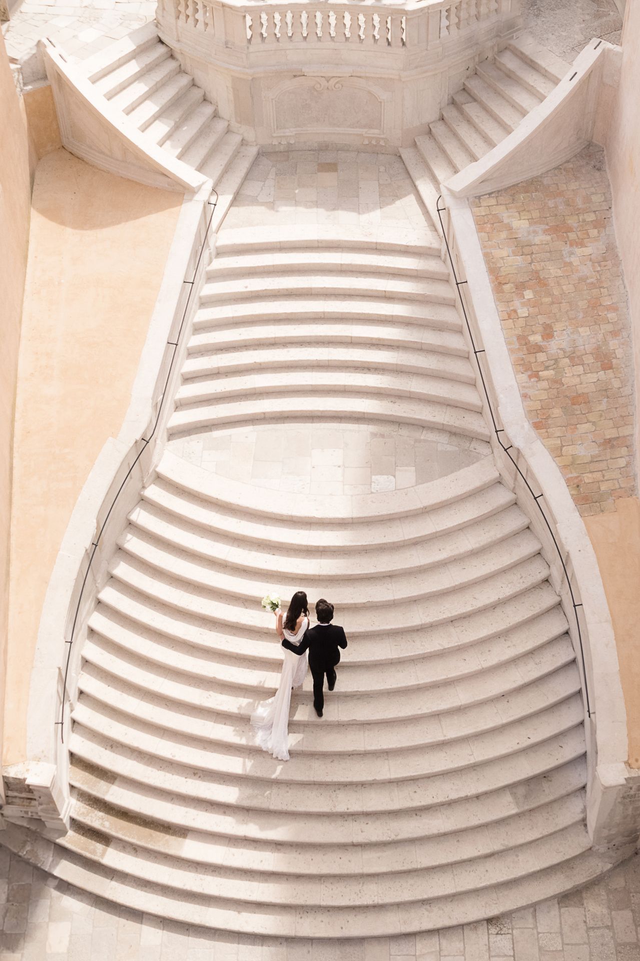 Two figures descending curved stone amphitheater steps viewed from above.