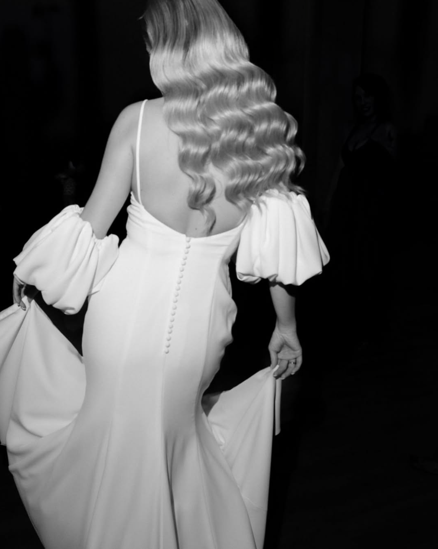 Back view of flowing white wedding dress with button details in black and white photography.