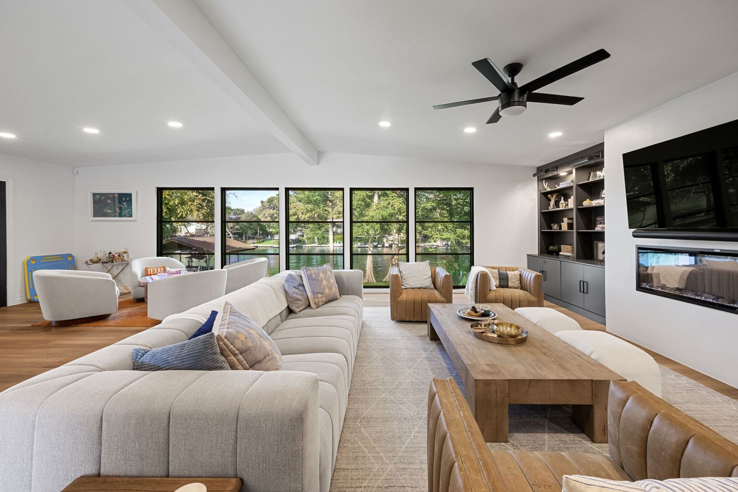 Spacious open-concept living room with large sectional sofa, wood coffee table, built-in shelves, and lake views.
