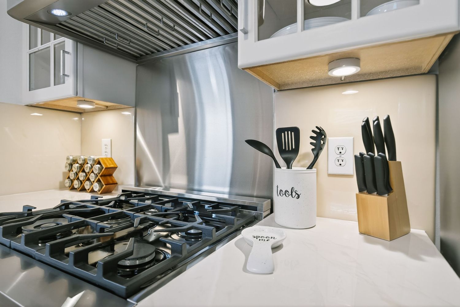 Modern kitchen interior with stainless steel appliances, gas cooktop, and white cabinetry in a contemporary design.