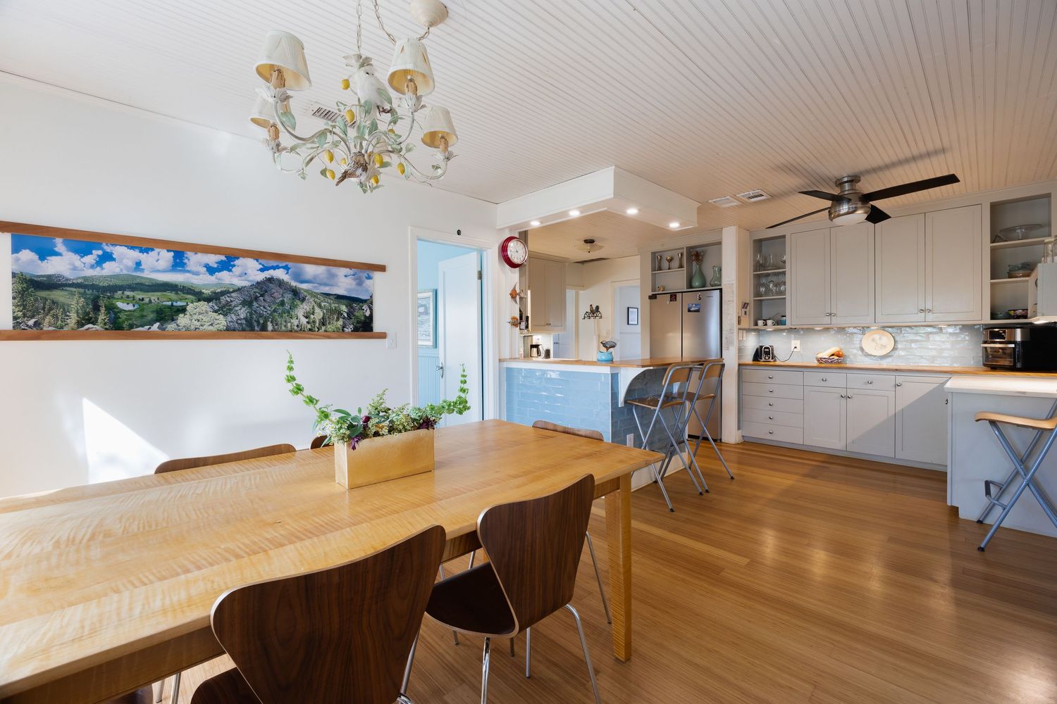 Contemporary dining space with wooden table and ceiling fan under beadboard ceiling.